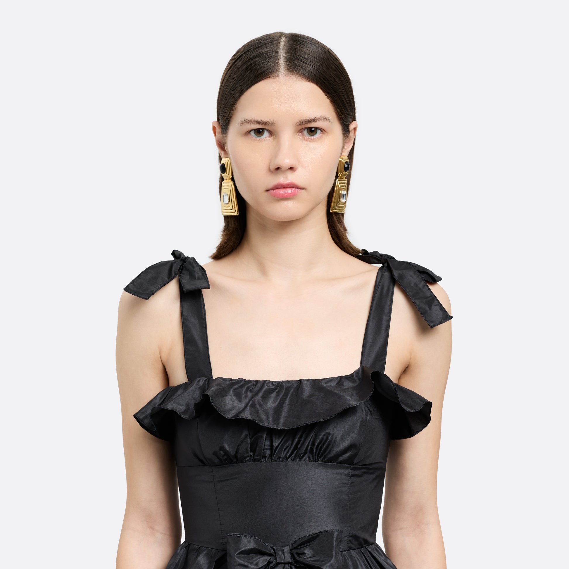 Gold-tone metal clip-on earrings with a black crystal detail and clear crystal pendant drop.

Featured in the Fall Winter 2026 Lookbook.