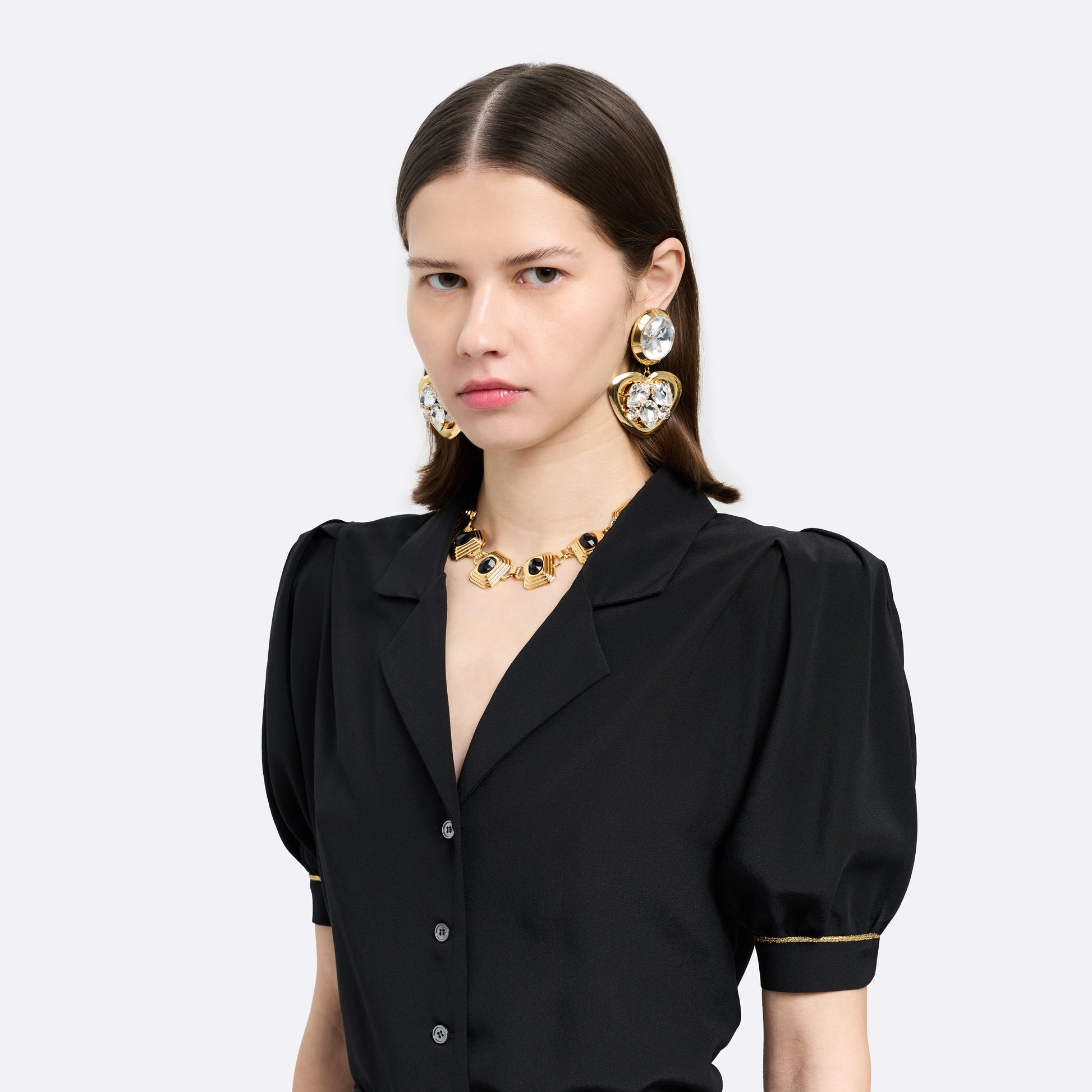 Gold-tone metal clip-on earrings with crystal details and a heart-shaped pendant.

Featured in the Fall Winter 2026 Lookbook.