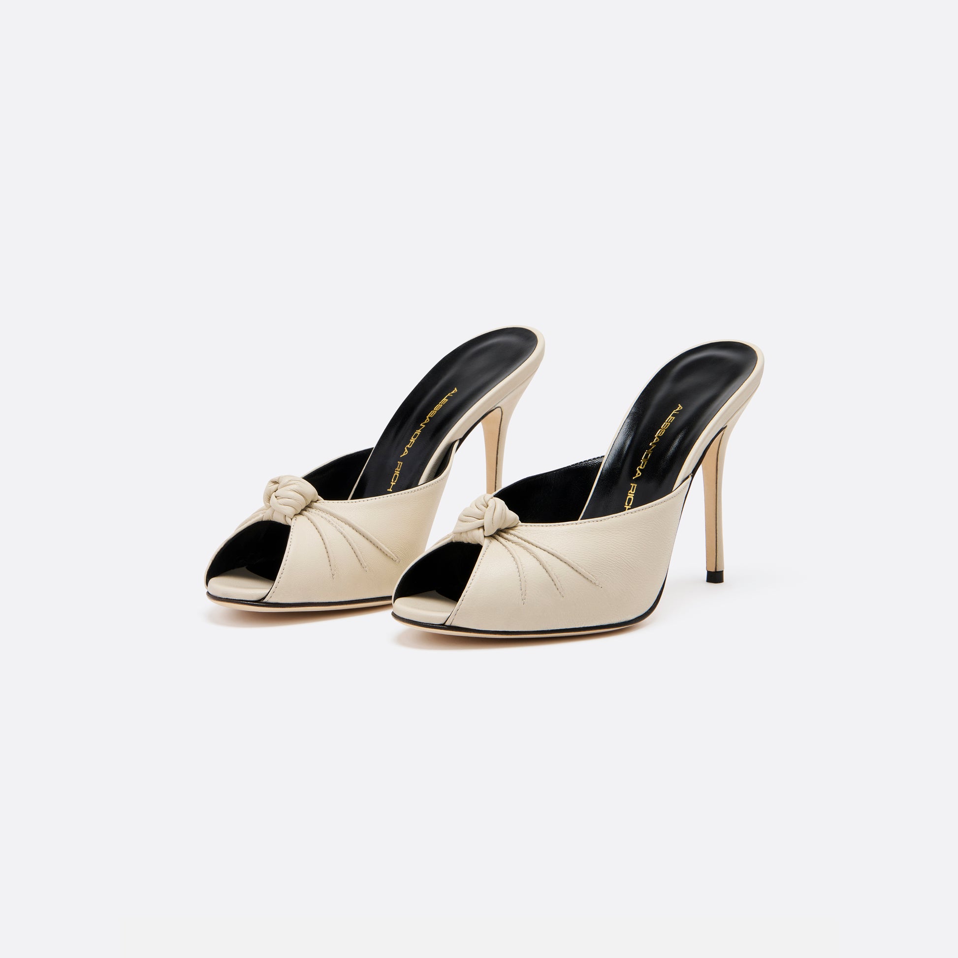 Cream leather mules with a peep toe and a 10.5 cm stiletto heel. Finished with a central knot detail.