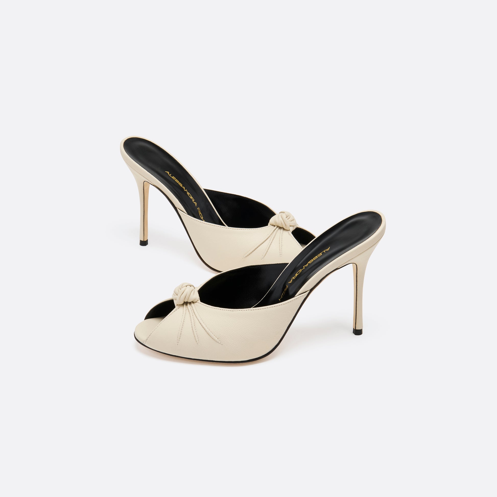 Cream leather mules with a peep toe and a 10.5 cm stiletto heel. Finished with a central knot detail.