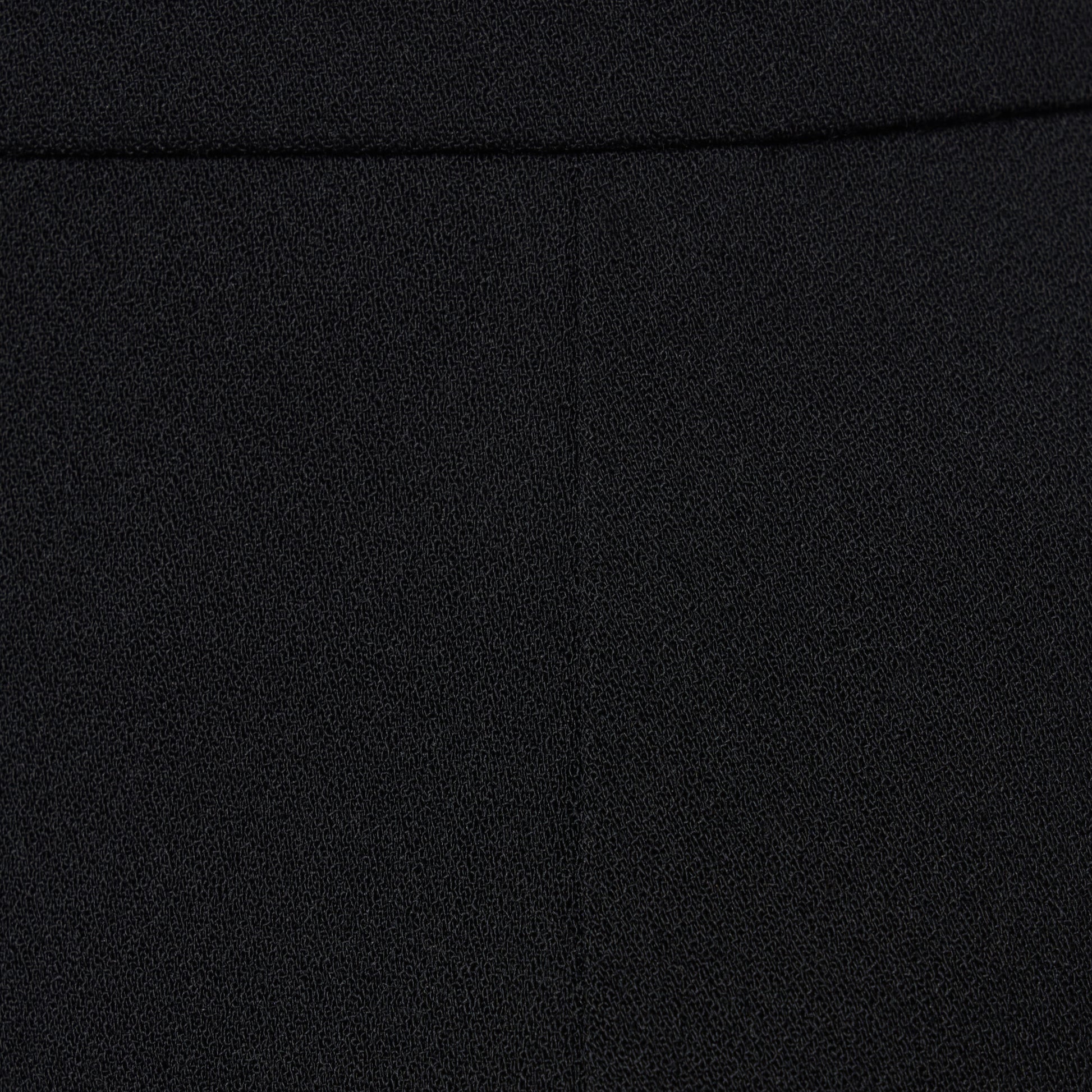 Black wool crêpe mini skirt with a high waist and a fitted silhouette.