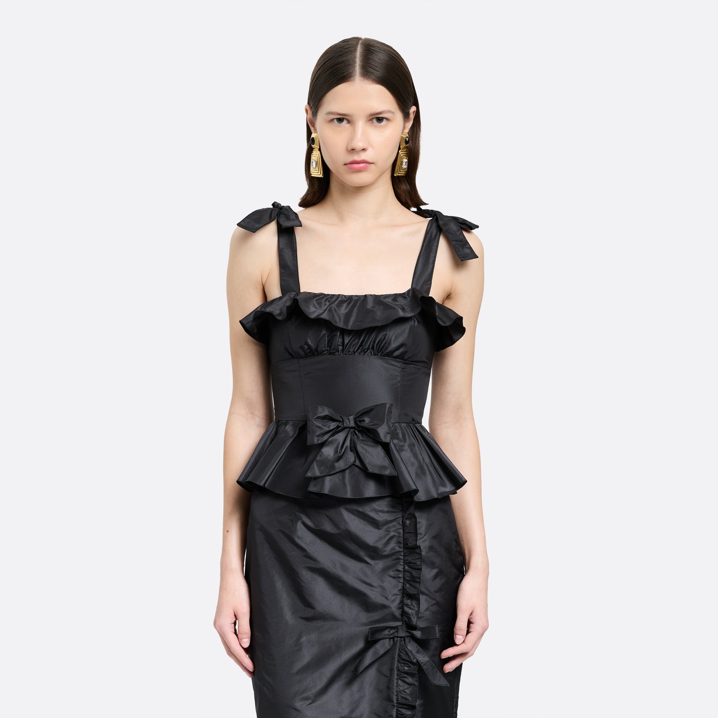 Black silk taffeta midi dress with self-tie shoulder straps and a ruffled neckline. A peplum defines the silhouette, while the straight skirt is finished with a delicate ruffle trim at the split.

Look 22 – Fall Winter 2026 Lookbook.