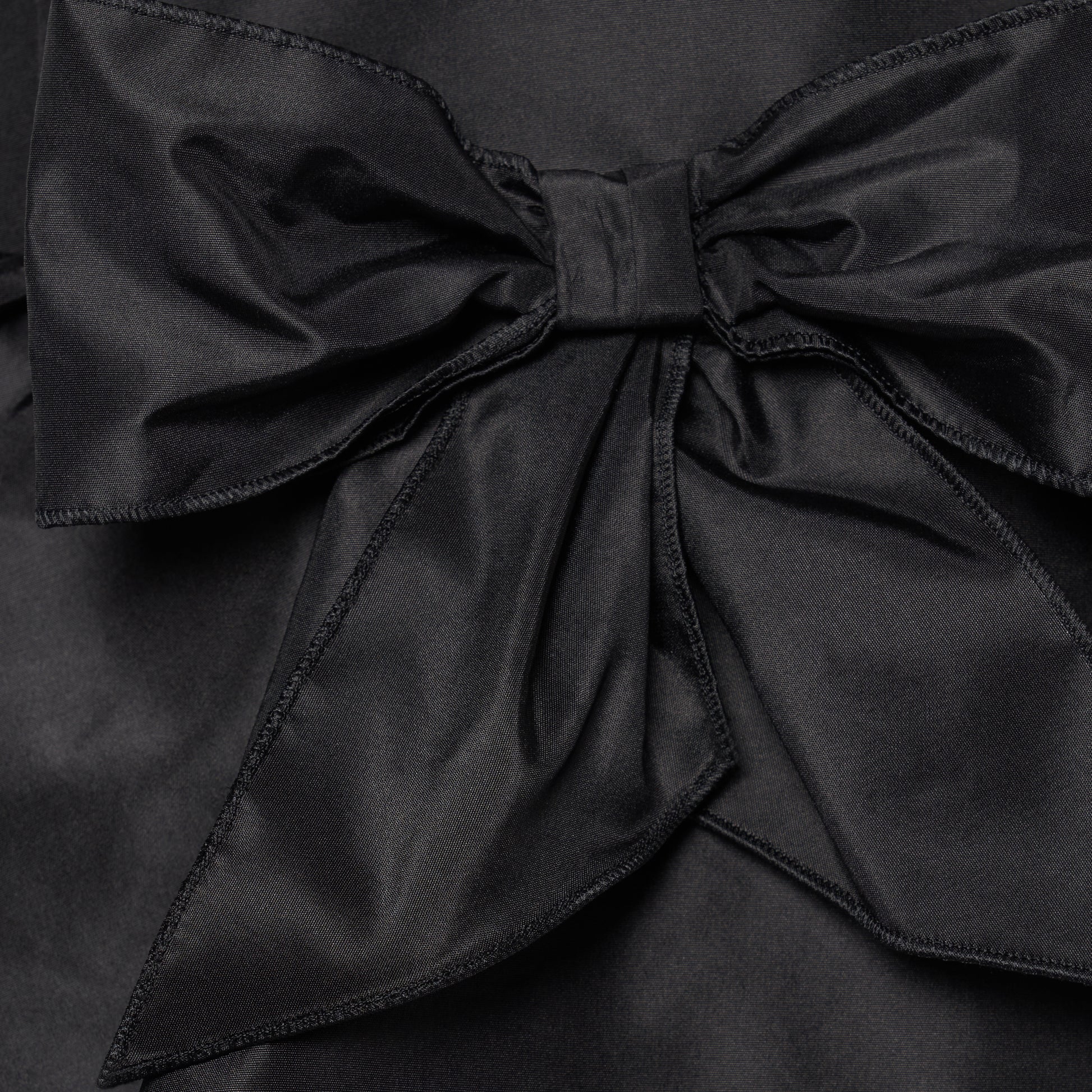 Black silk taffeta midi dress with self-tie shoulder straps and a ruffled neckline. A peplum defines the silhouette, while the straight skirt is finished with a delicate ruffle trim at the split.

Look 22 – Fall Winter 2026 Lookbook.