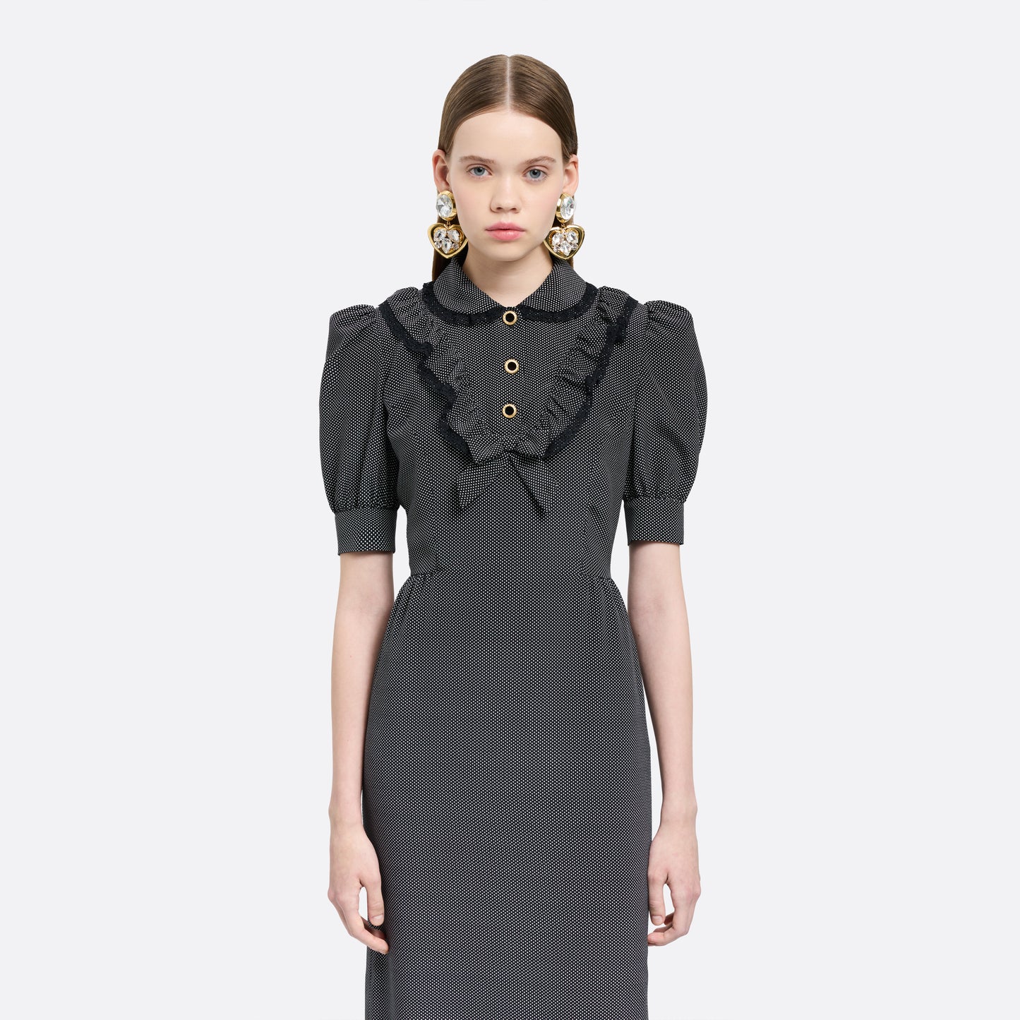 Black and white small polka-dot print silk crêpe de chine midi dress with short puffed sleeeves and black and old tone buttons. Finished with a lace trimmed collar and ruffled bib detailing.

Look 31 – Fall Winter 2026 Lookbook.