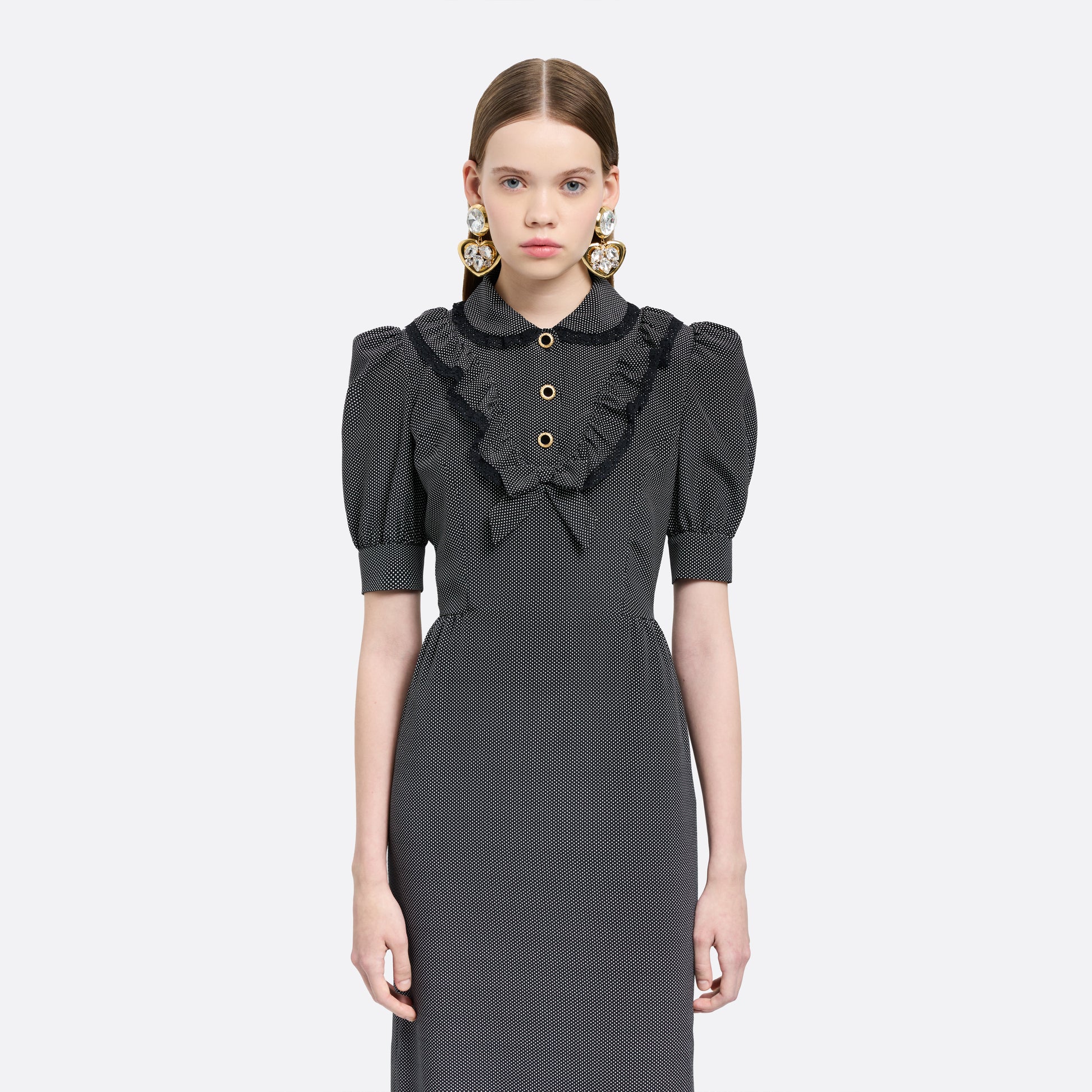 Black and white small polka-dot print silk crêpe de chine midi dress with short puffed sleeeves and black and old tone buttons. Finished with a lace trimmed collar and ruffled bib detailing.

Look 31 – Fall Winter 2026 Lookbook.