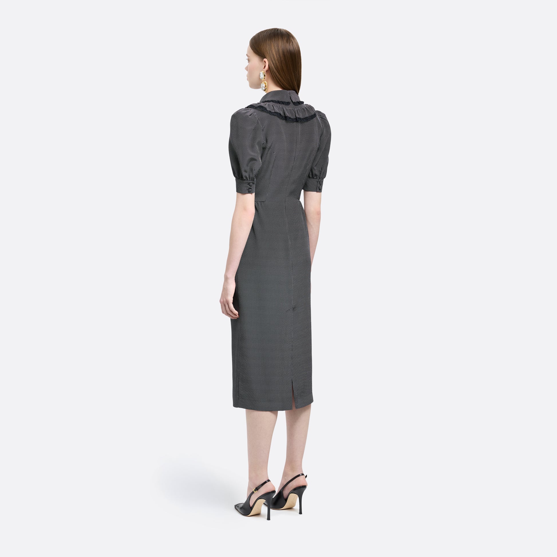 Black and white small polka-dot print silk crêpe de chine midi dress with short puffed sleeeves and black and old tone buttons. Finished with a lace trimmed collar and ruffled bib detailing.

Look 31 – Fall Winter 2026 Lookbook.