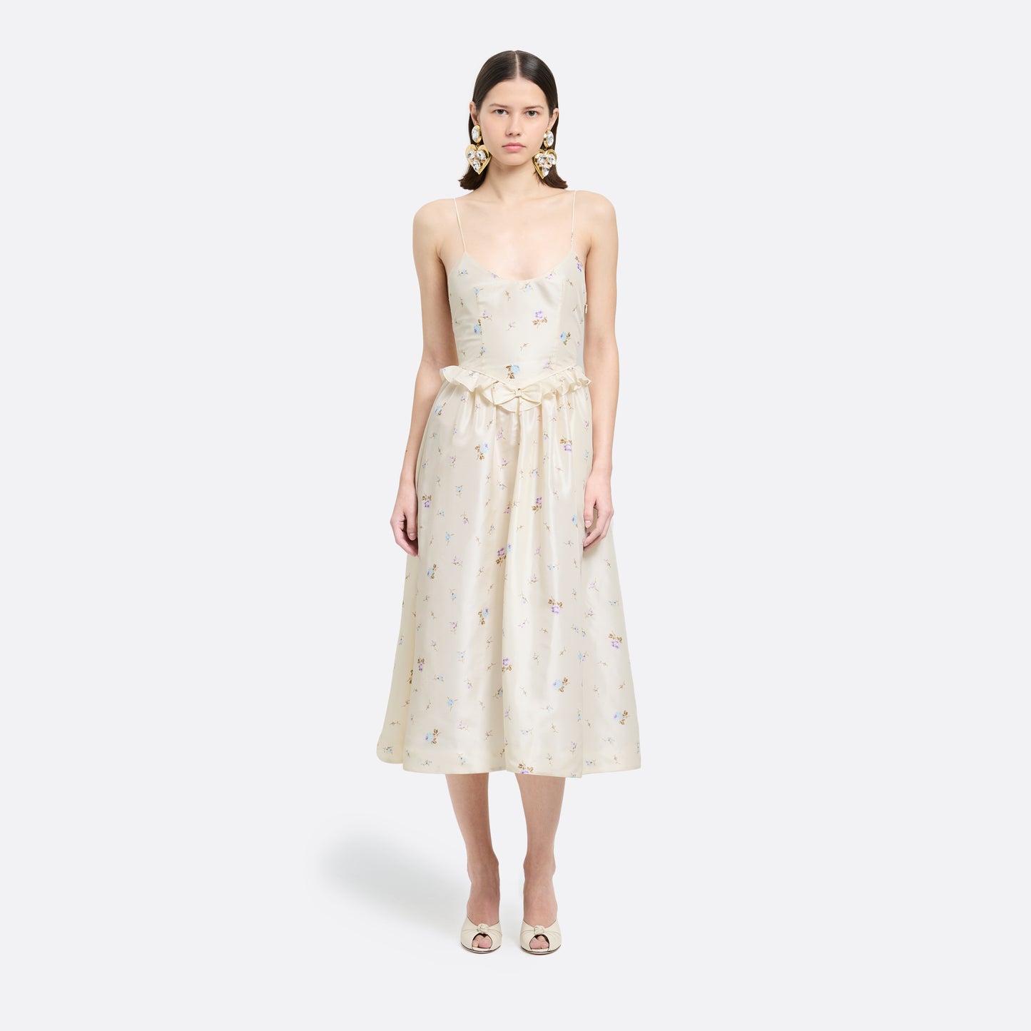 Floral-print white silk taffeta midi dress with spaghetti straps and a scoop neckline. The silhouette is finished with a flared skirt with pockets and a ruffled waist with a bow.