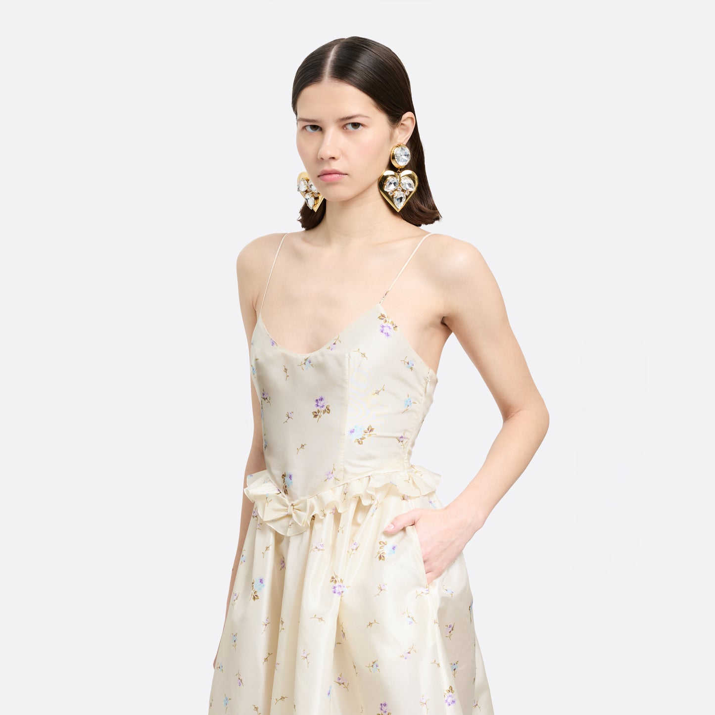 Floral-print white silk taffeta midi dress with spaghetti straps and a scoop neckline. The silhouette is finished with a flared skirt with pockets and a ruffled waist with a bow.