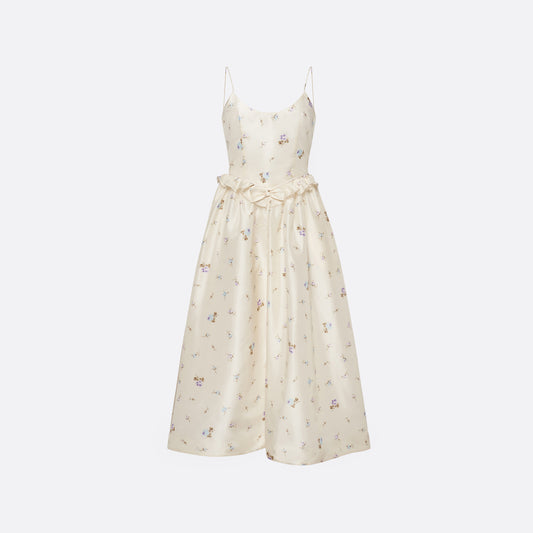 Floral-print white silk taffeta midi dress with spaghetti straps and a scoop neckline. The silhouette is finished with a flared skirt with pockets and a ruffled waist with a bow.