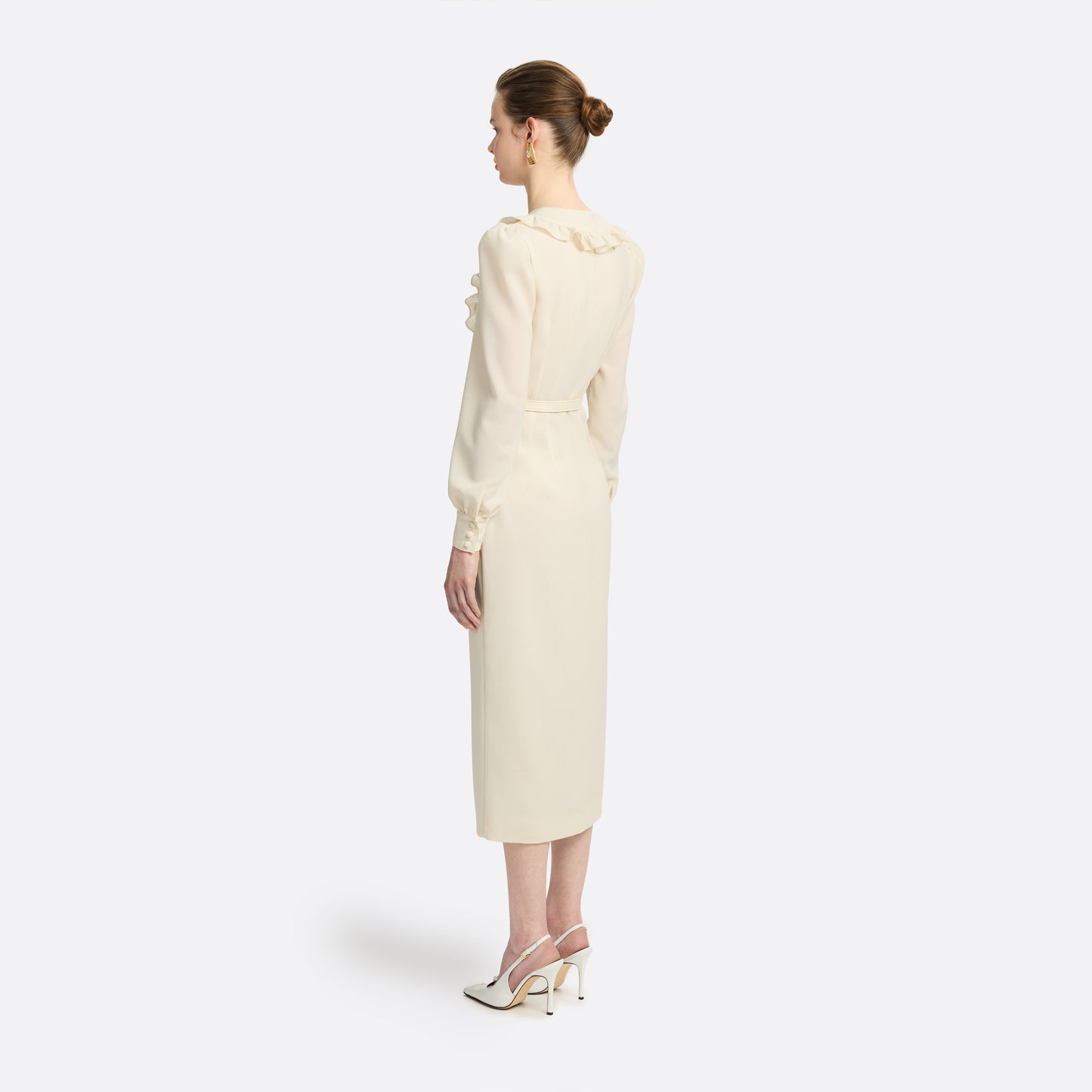 Cream light wool crêpe midi dress with a deep V-neckline framed by a ruffle-trimmed collar and long sleeves. Finished with a front button closure accented by black and gold-tone buttons and a slim belt.

Look 10 – Fall Winter 2026 Lookbook.