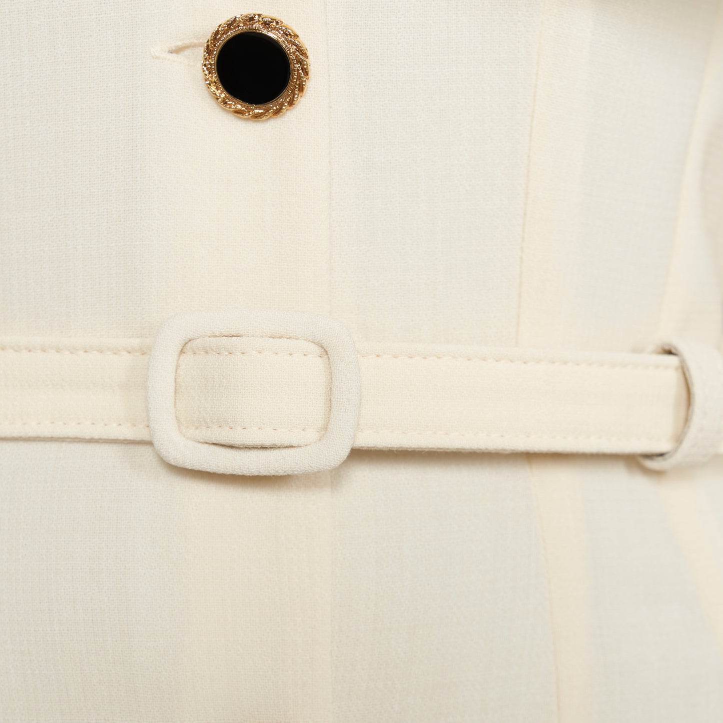 Cream light wool crêpe midi dress with a deep V-neckline framed by a ruffle-trimmed collar and long sleeves. Finished with a front button closure accented by black and gold-tone buttons and a slim belt.

Look 10 – Fall Winter 2026 Lookbook.