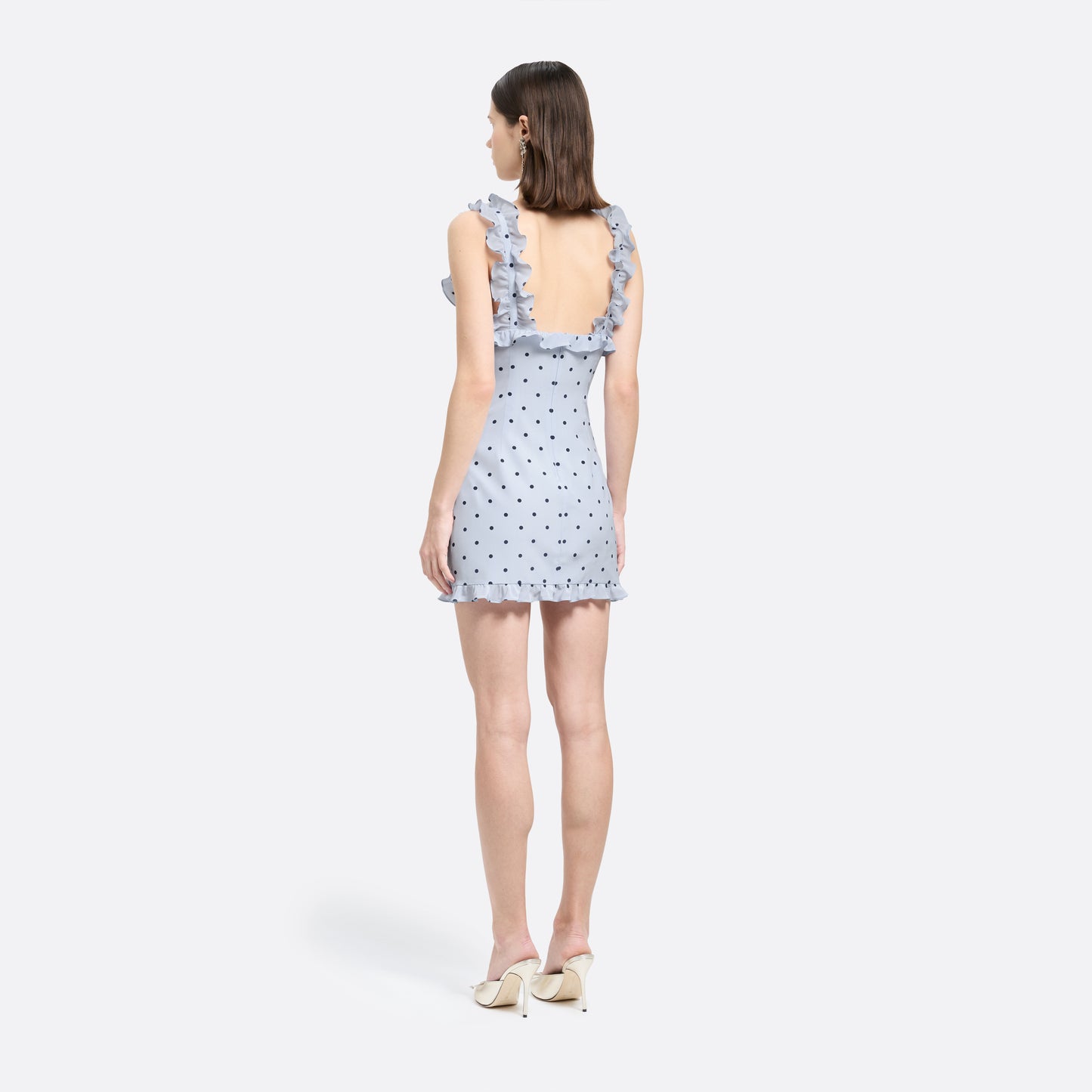 Light blue polka-dot silk crêpe de chine mini dress with bow-detailed shoulder straps and a ruffled neckline. The fitted silhouette is finished with patch pockets and a ruffled hem.