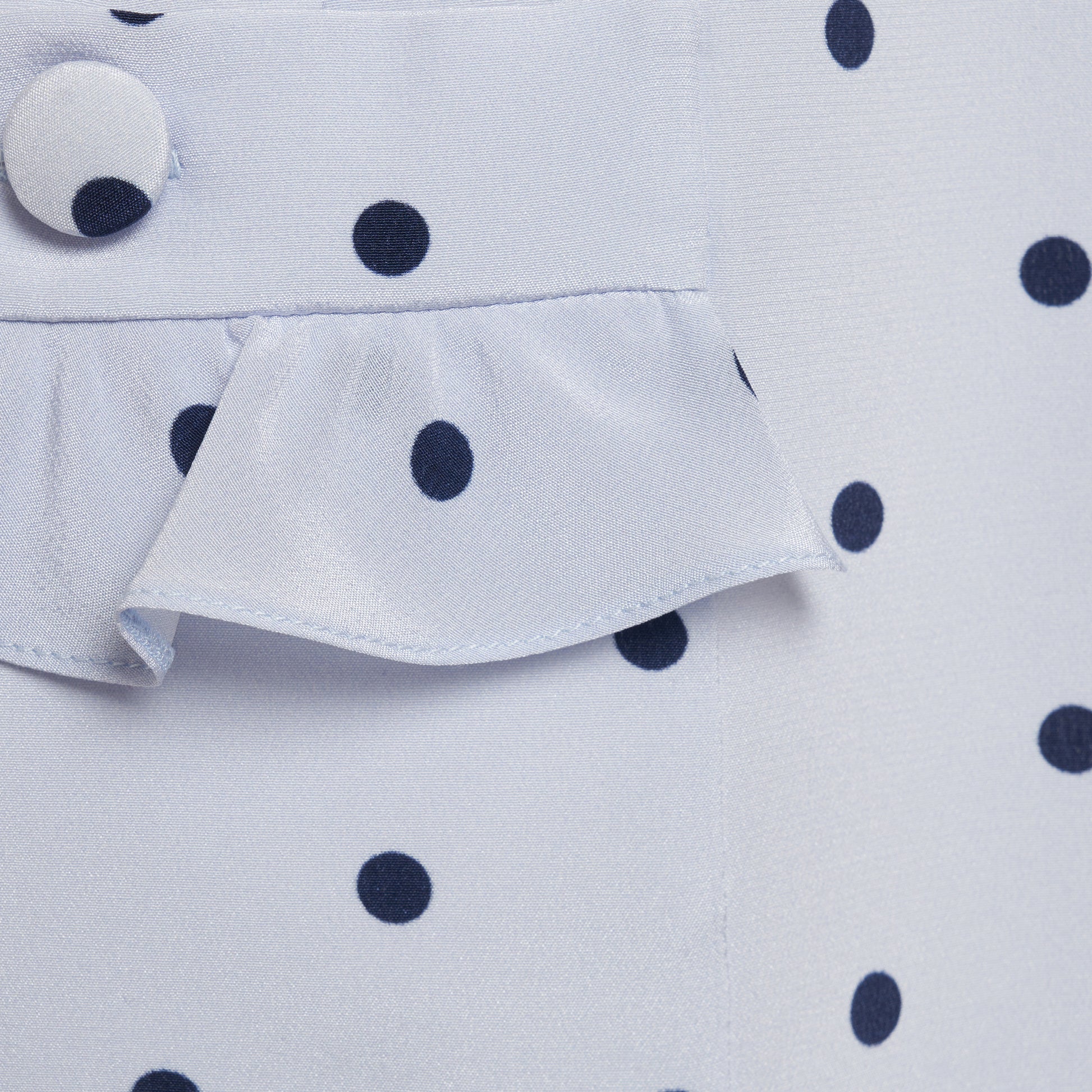 Light blue polka-dot silk crêpe de chine mini dress with bow-detailed shoulder straps and a ruffled neckline. The fitted silhouette is finished with patch pockets and a ruffled hem.