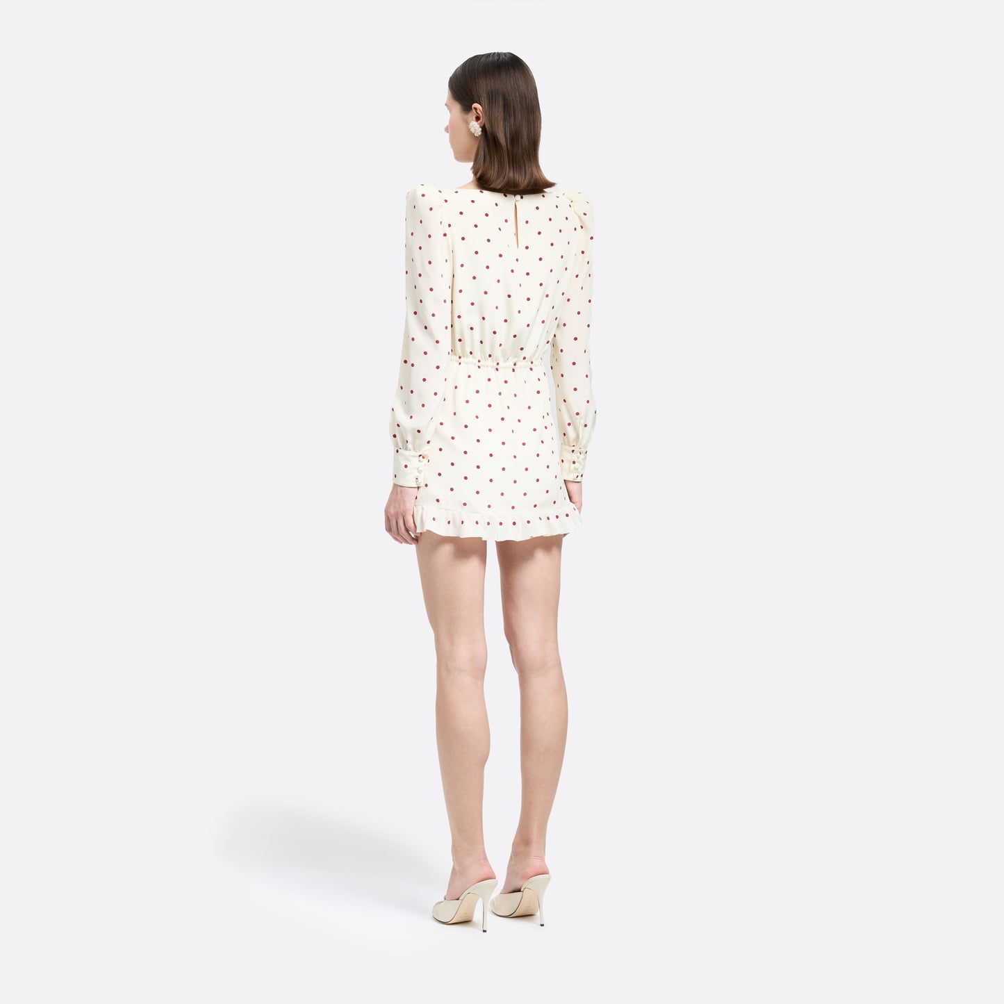 Cream and bordeaux polka-dot silk crêpe de chine mini dress with a scooped neckline and long sleeves. Defined by a drawstring waist, the silhouette is finished with patch pockets and a volant hem.
