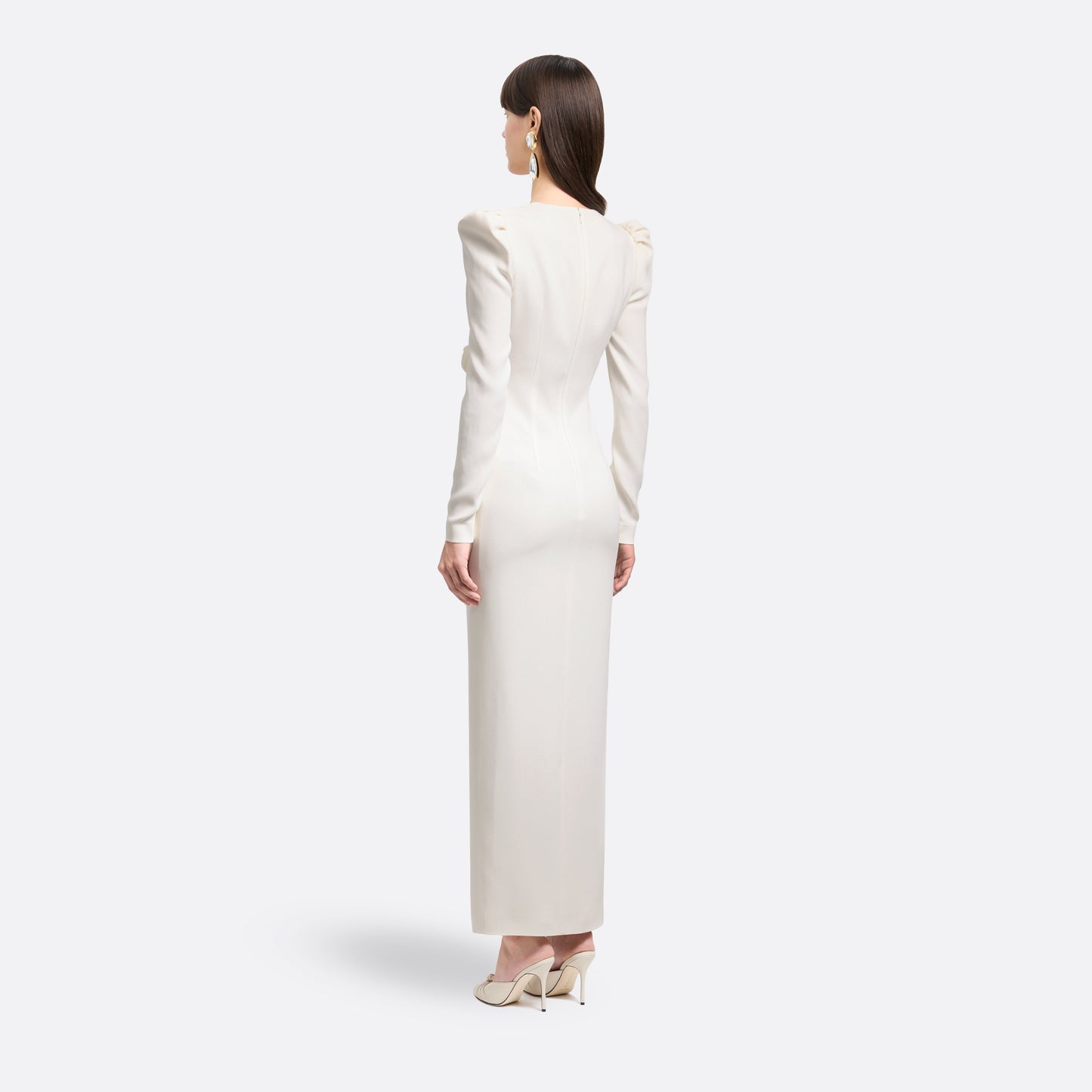 White cady evening dress cut to a fitted silhouette with a V-neckline and long sleeves. Finished with a bow detail and front split.