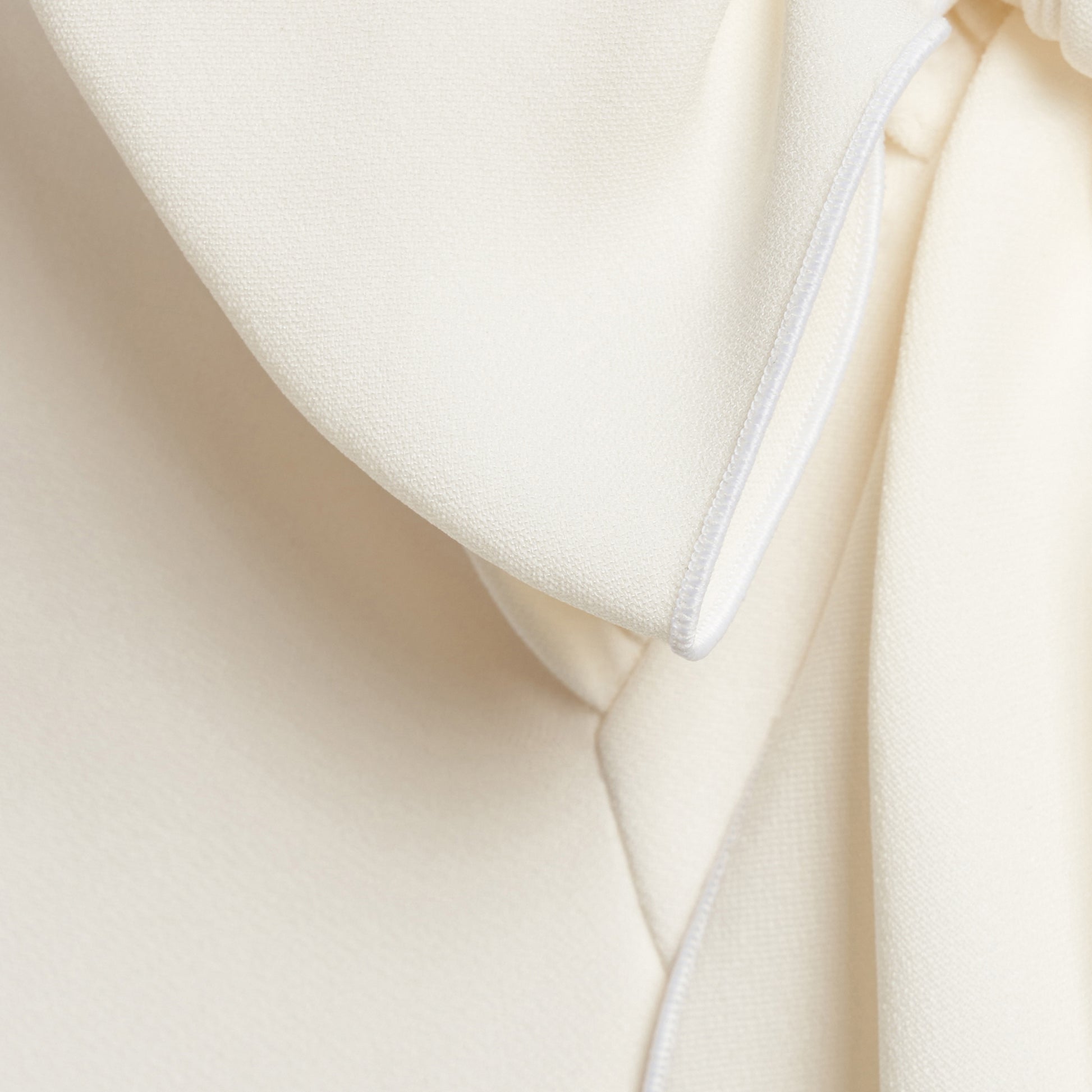 White cady evening dress cut to a fitted silhouette with a V-neckline and long sleeves. Finished with a bow detail and front split.