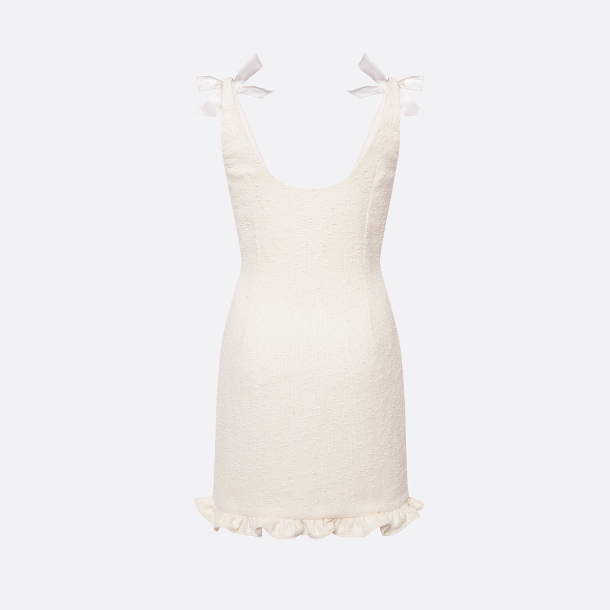 White tweed bouclé mini dress with a fitted silhouette and a soft ruffle at the hem. The shoulder straps are finished with silk bows.