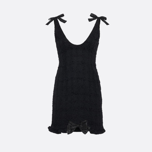 Black check tweed bouclé mini dress with a fitted silhouette and a soft ruffle at the hem. The shoulder straps are finished with bows.

Look 16 – Fall Winter 2026 Lookbook.