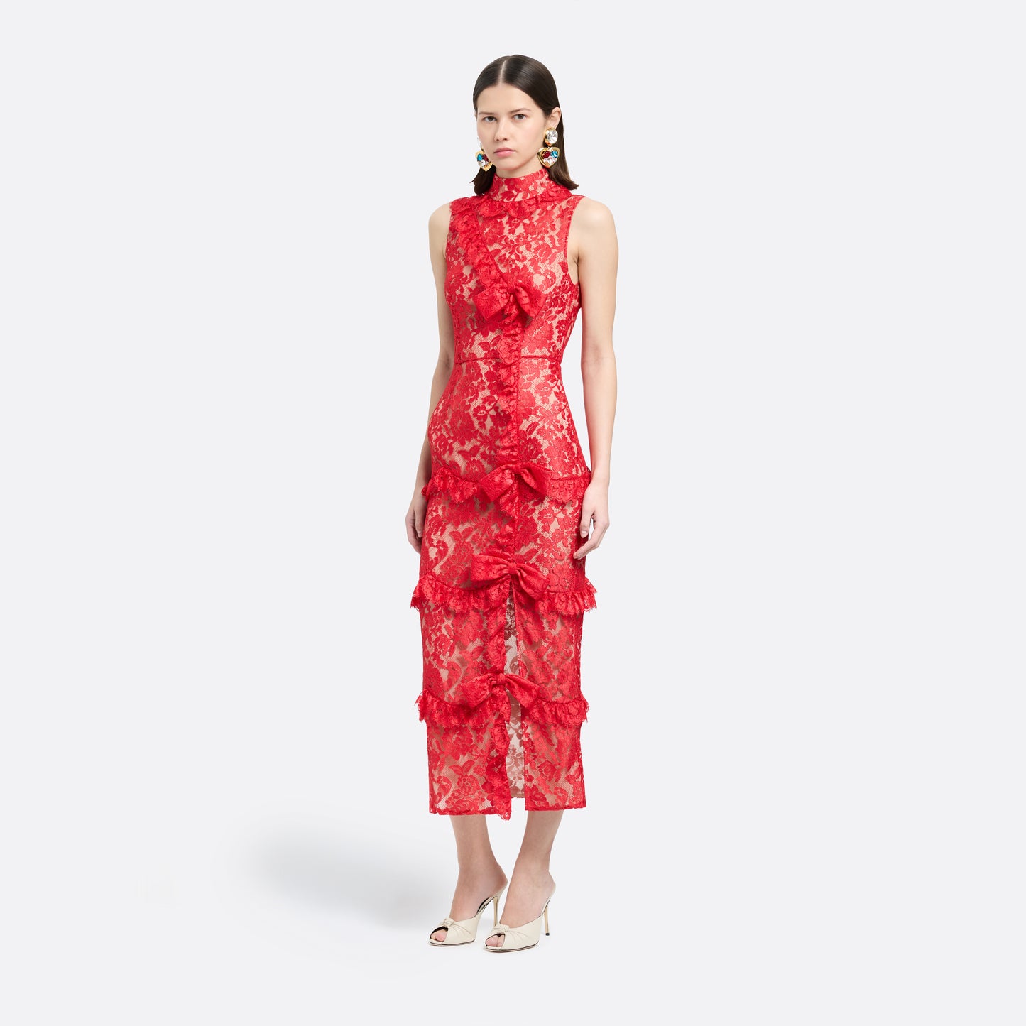 Red lace sleeveless evening dress with a high neckline and a fitted silhouette with a split. Finished with ruffled trims and bows.