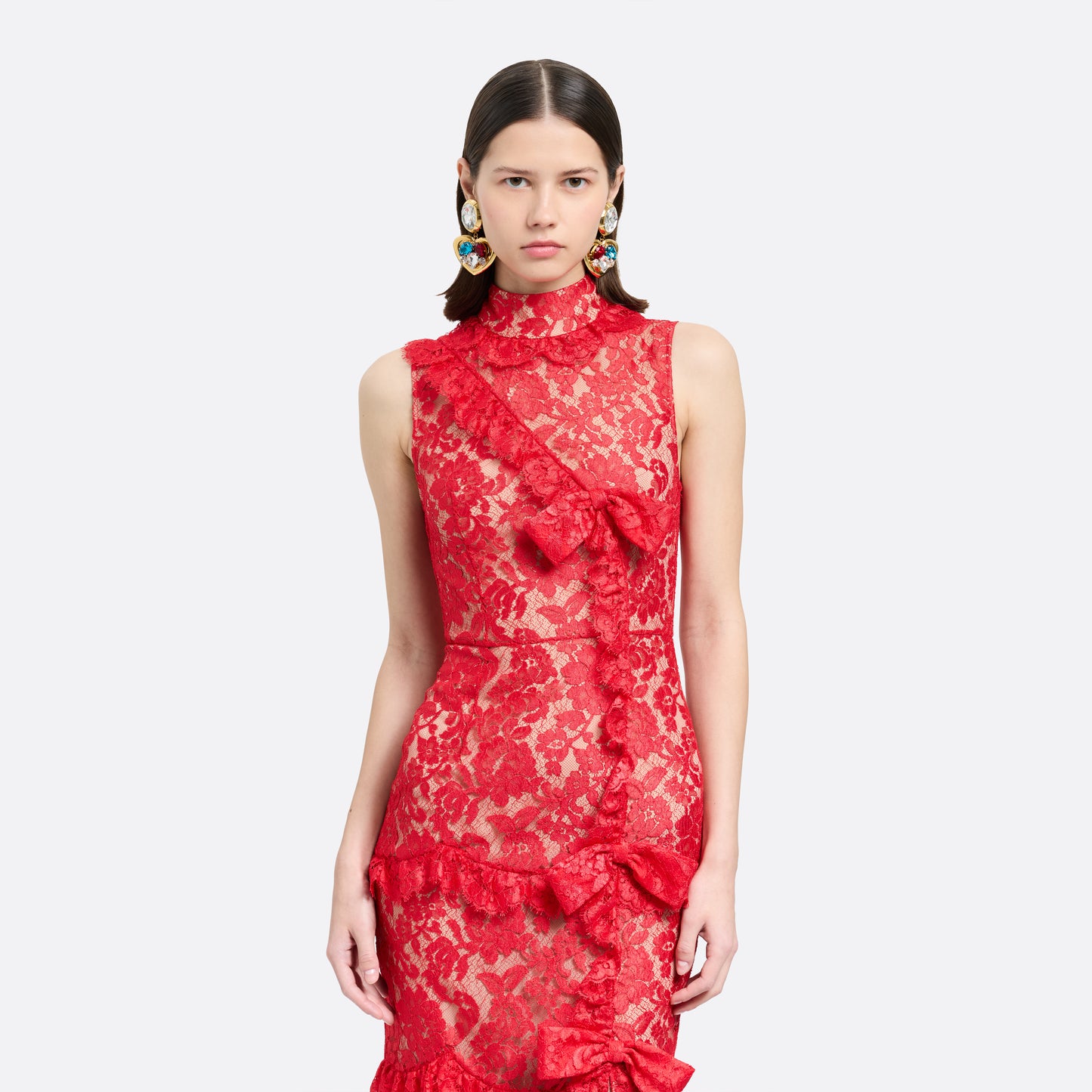 Red lace sleeveless evening dress with a high neckline and a fitted silhouette with a split. Finished with ruffled trims and bows.