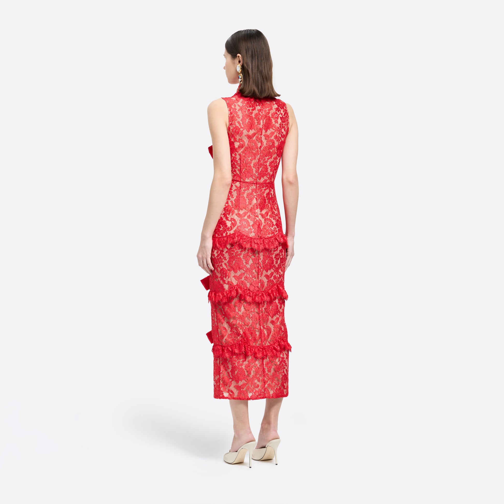 Red lace sleeveless evening dress with a high neckline and a fitted silhouette with a split. Finished with ruffled trims and bows.