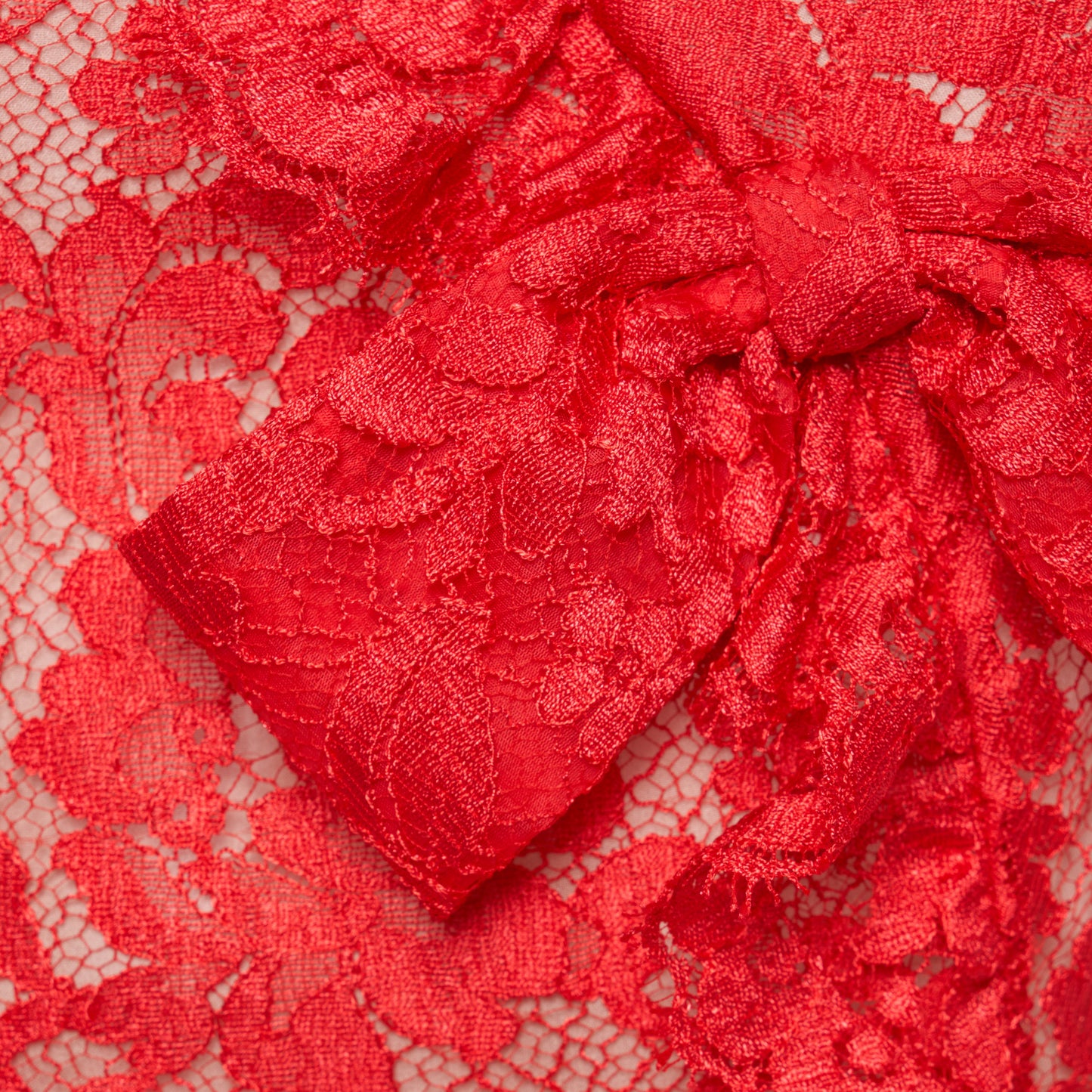 Red lace sleeveless evening dress with a high neckline and a fitted silhouette with a split. Finished with ruffled trims and bows.