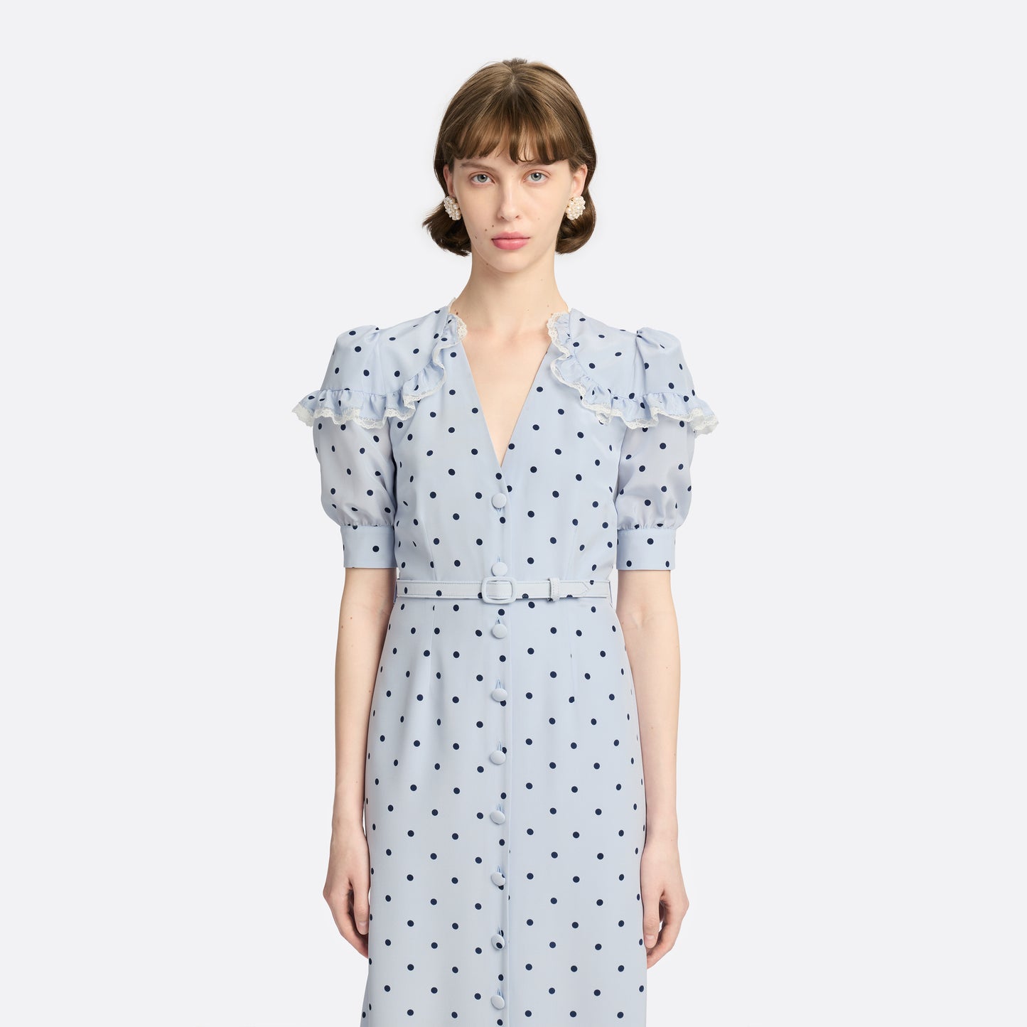 Light blue polka-dot silk midi dress with a V-neckline, front button closure and short puff sleeves detailed with lace-trimmed ruffles. Finished with a slim belt.