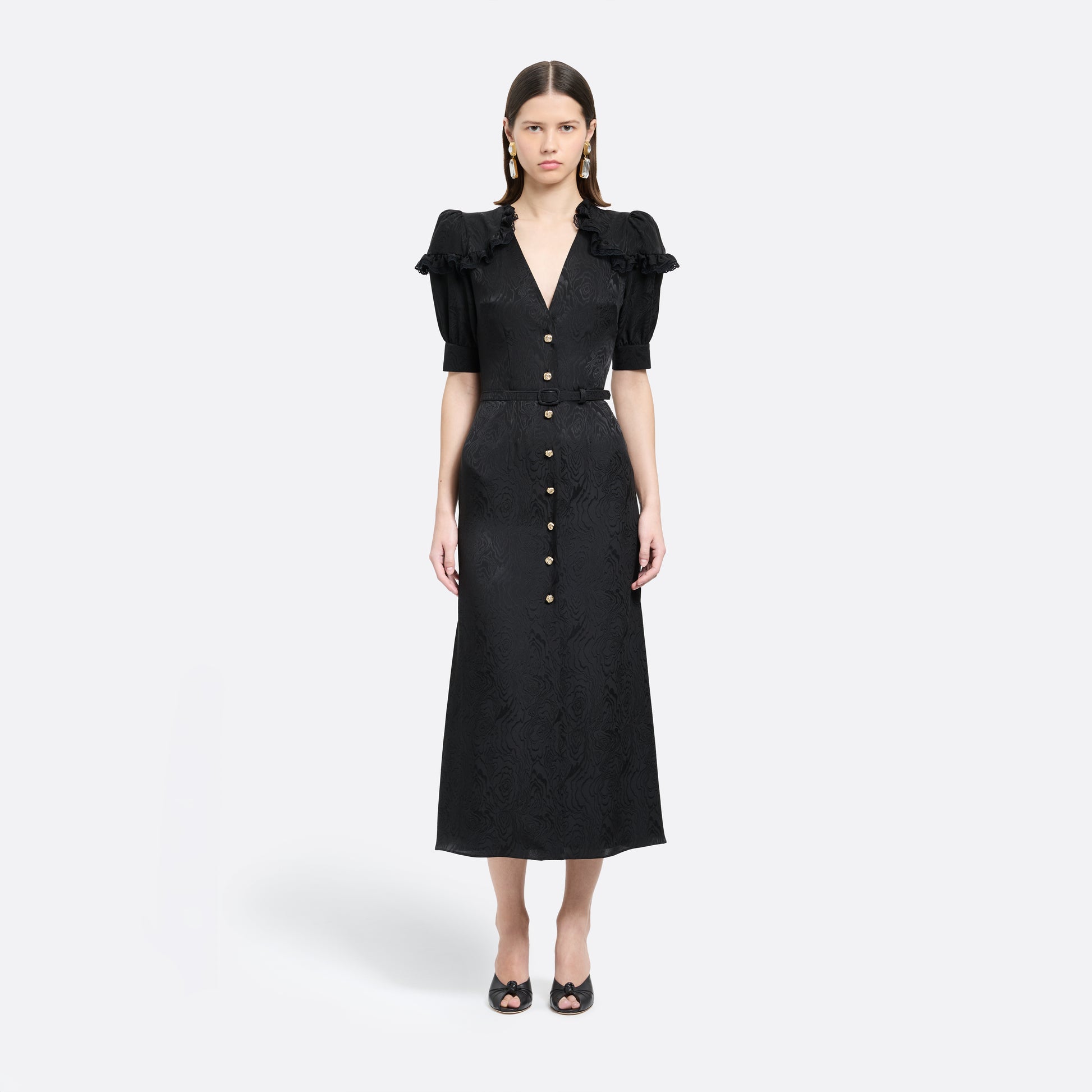 Black moiré silk jacquard midi dress with a V-neckline, front button closure and short puff sleeves detailed with lace-trimmed ruffles. Finished with jewel buttons and a slim belt.