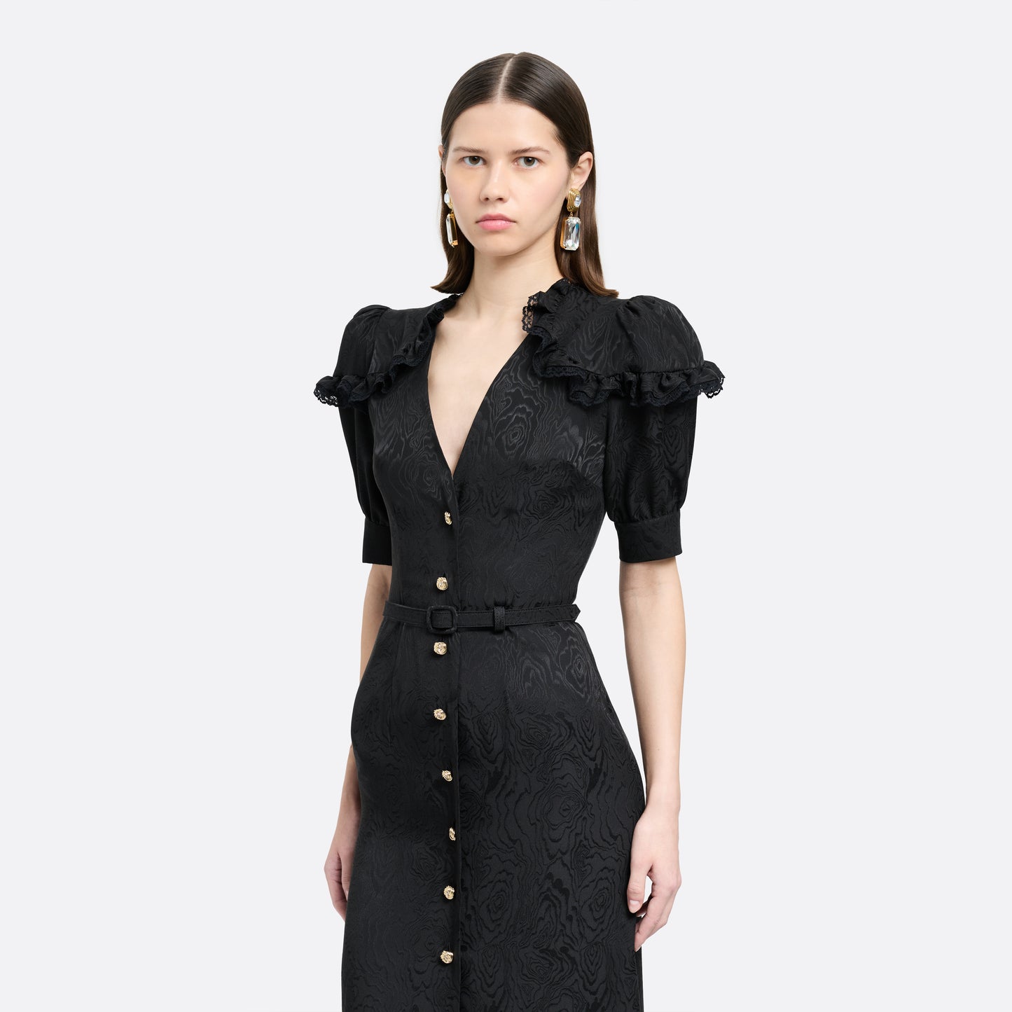 Black moiré silk jacquard midi dress with a V-neckline, front button closure and short puff sleeves detailed with lace-trimmed ruffles. Finished with jewel buttons and a slim belt.