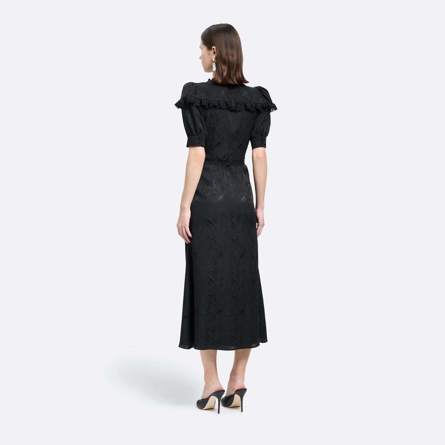 Black moiré silk jacquard midi dress with a V-neckline, front button closure and short puff sleeves detailed with lace-trimmed ruffles. Finished with jewel buttons and a slim belt.