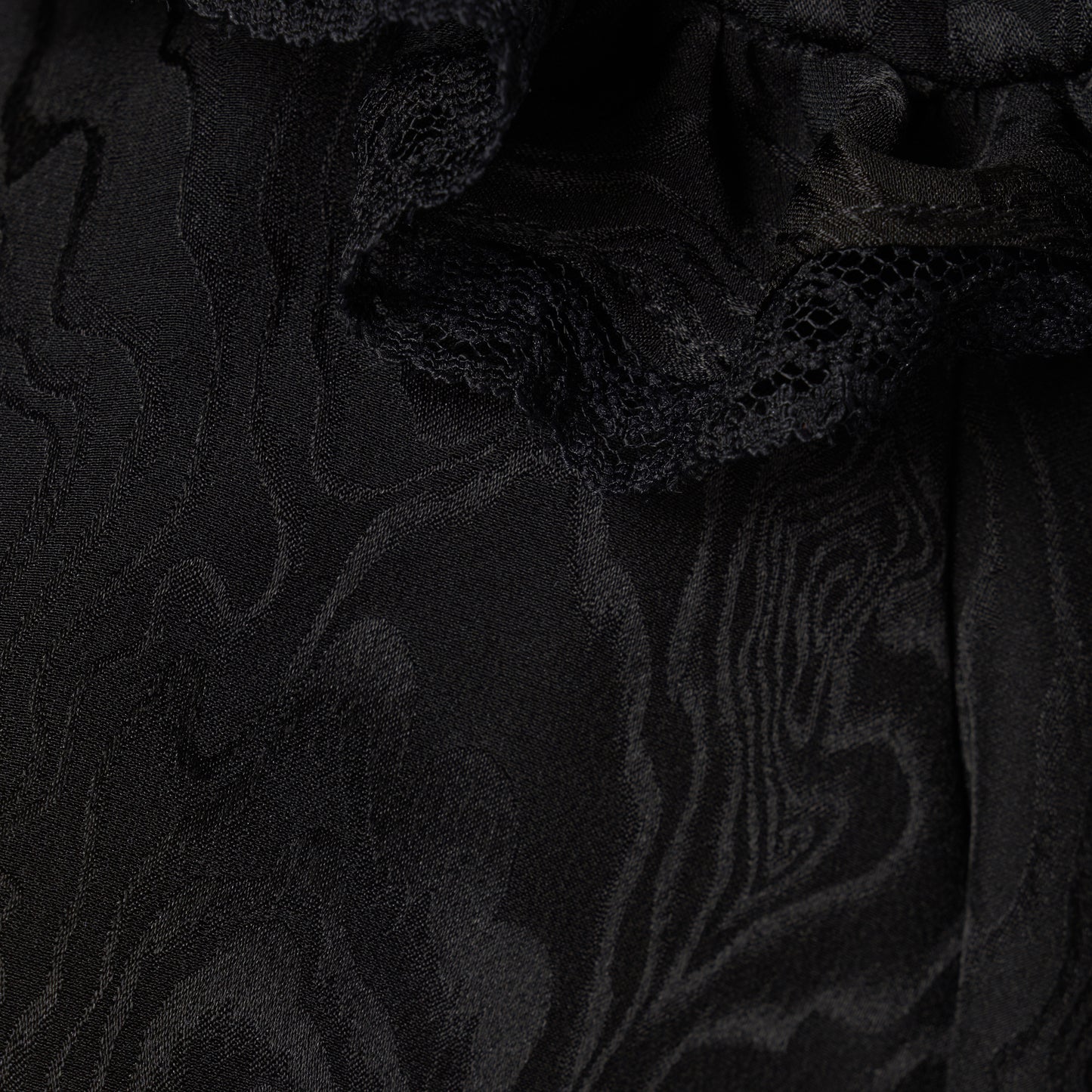 Black moiré silk jacquard midi dress with a V-neckline, front button closure and short puff sleeves detailed with lace-trimmed ruffles. Finished with jewel buttons and a slim belt.