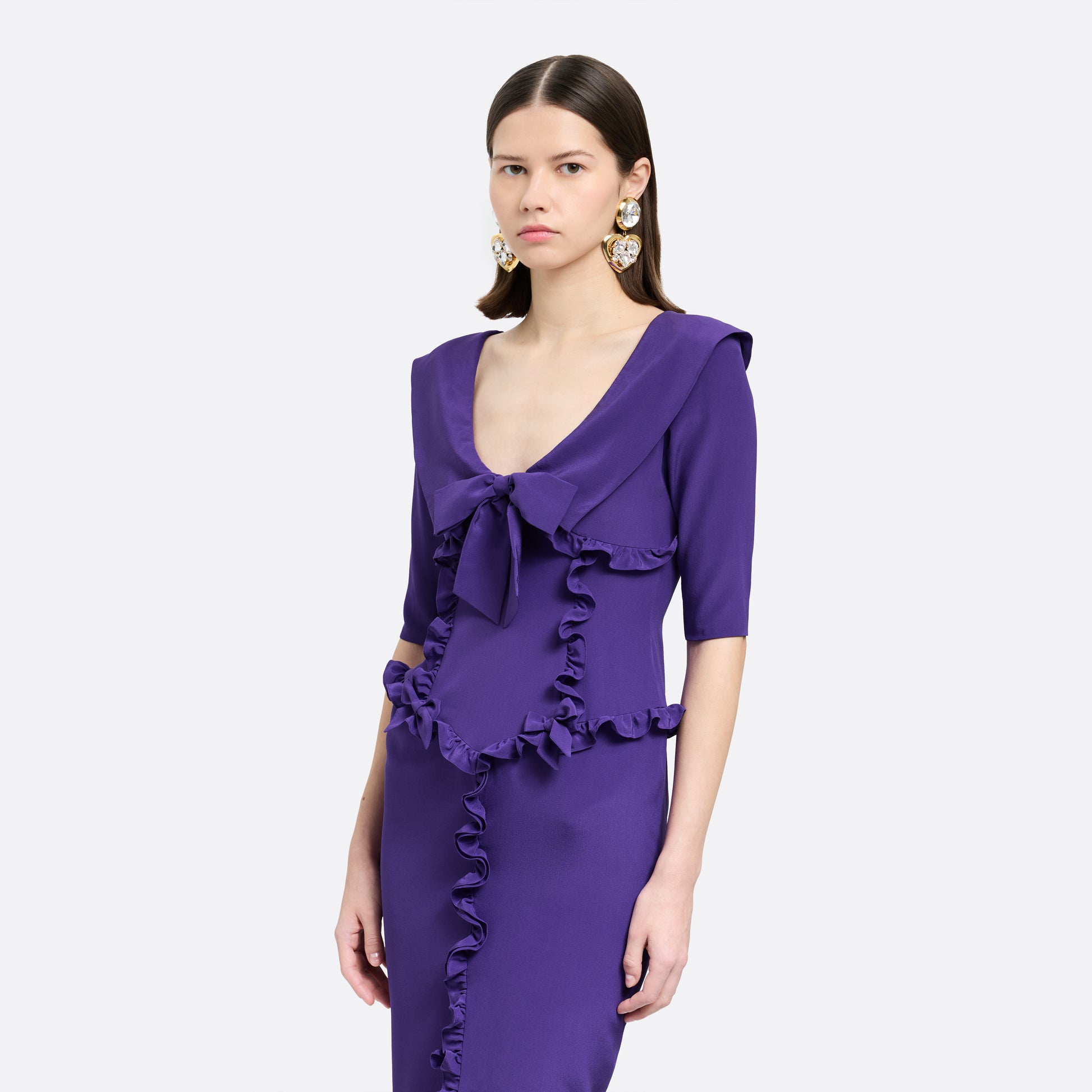 Purple silk crêpe de chine dress with a wide collar, ruffle details, bows and a centre split.

Look 7 – Fall Winter 2026 Lookbook.