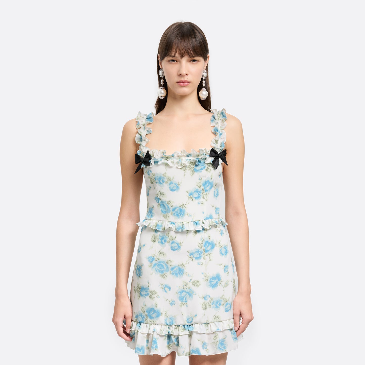 Light blue and white floral-print silk crêpe de chine mini dress with bow-detailed shoulder straps and a ruffled neckline. The silhouette is defined by ruffles at the waist and hem.