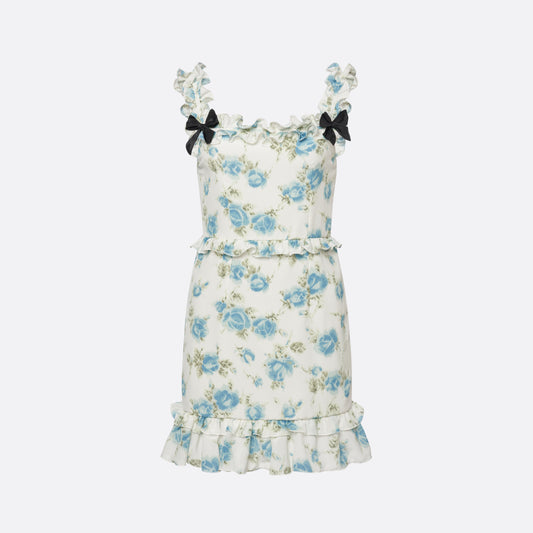 Light blue and white floral-print silk crêpe de chine mini dress with bow-detailed shoulder straps and a ruffled neckline. The silhouette is defined by ruffles at the waist and hem.