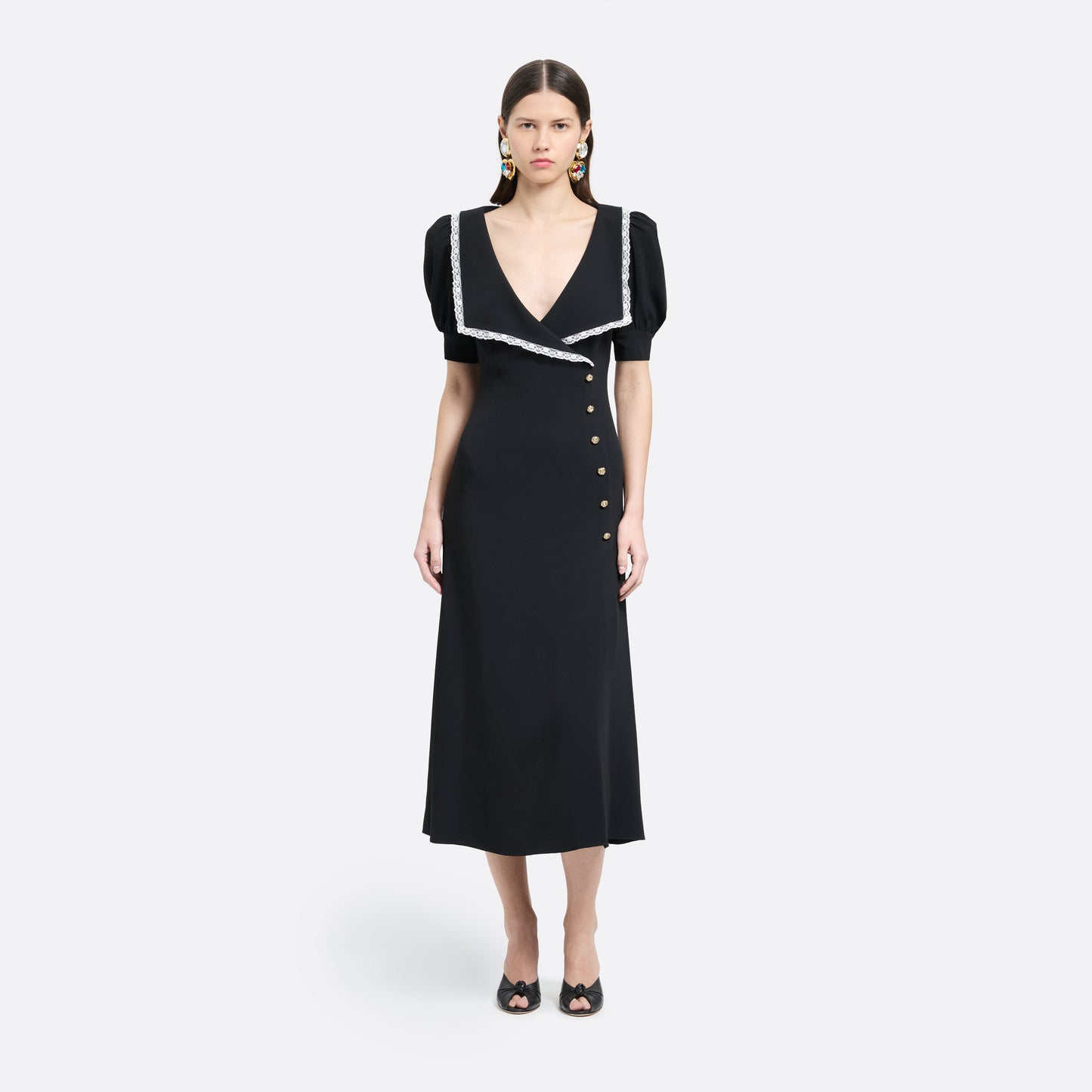 Black cady midi dress with a wrap-style silhouette and asymmetric button detailing. The wide collar is finished with a white lace trim.

Look 23 – Fall Winter 2026 Lookbook.