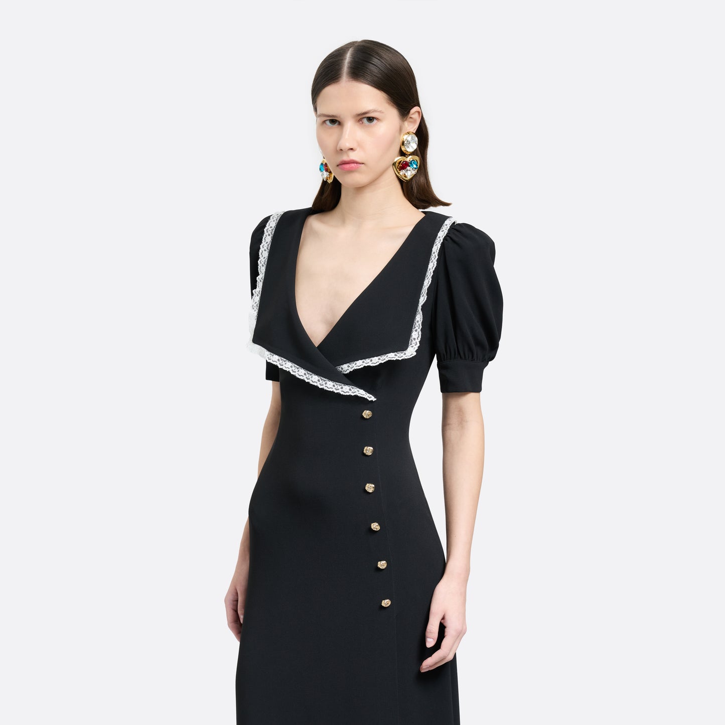 Black cady midi dress with a wrap-style silhouette and asymmetric button detailing. The wide collar is finished with a white lace trim.

Look 23 – Fall Winter 2026 Lookbook.