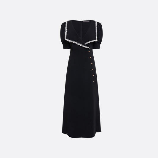 Black cady midi dress with a wrap-style silhouette and asymmetric button detailing. The wide collar is finished with a white lace trim.

Look 23 – Fall Winter 2026 Lookbook.