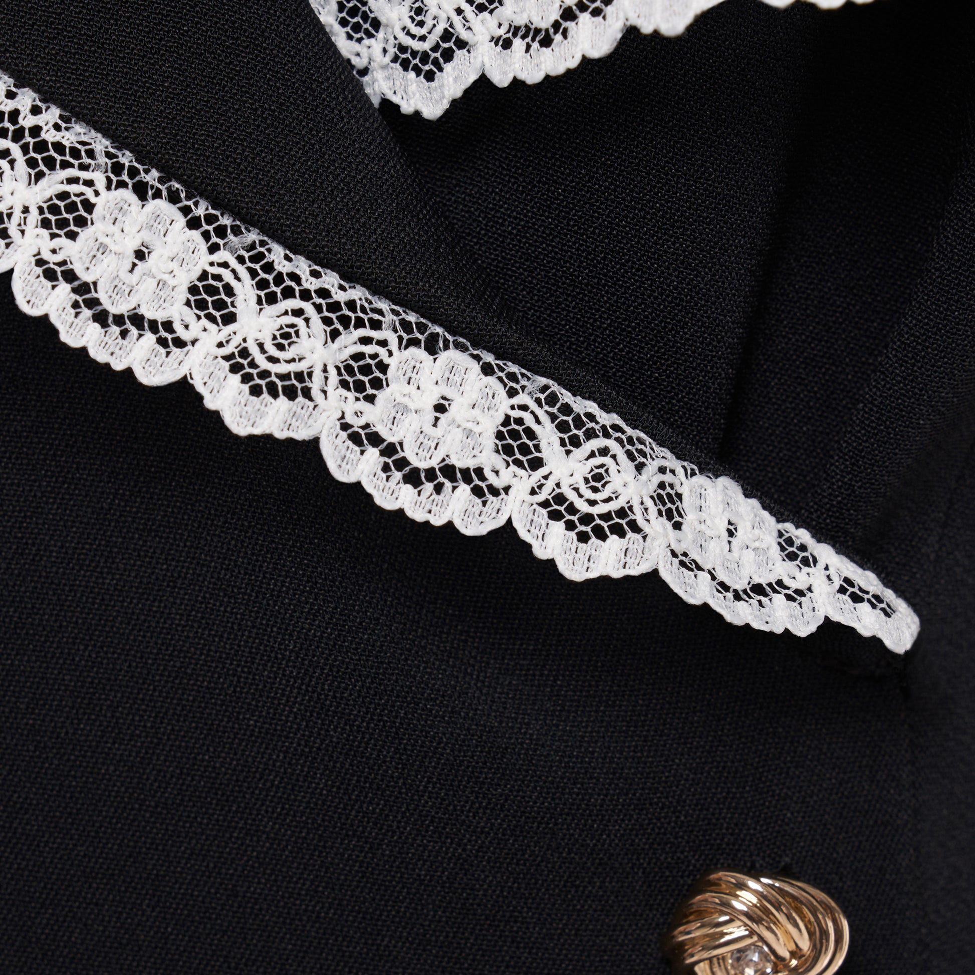 Black cady midi dress with a wrap-style silhouette and asymmetric button detailing. The wide collar is finished with a white lace trim.

Look 23 – Fall Winter 2026 Lookbook.