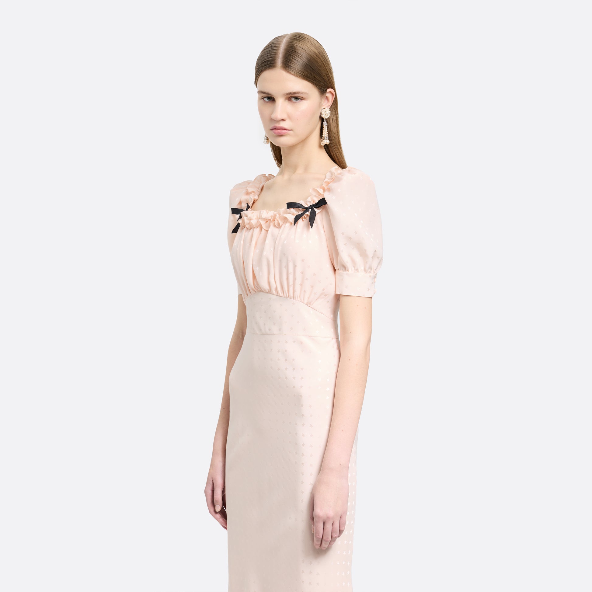Light pink star-jacquard silk midi dress with short puff sleeves and a square neckline detailed with black bows and a ruffled trim.