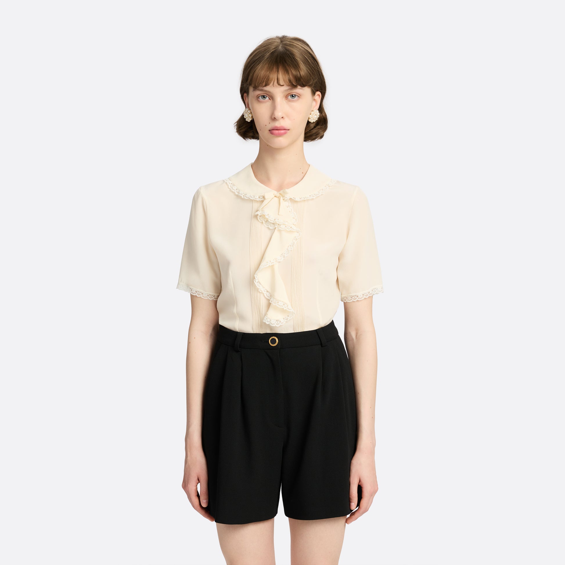 Cream silk crêpe de chine blouse with small collar, jabot and short sleeves all trimmed in lace and a back button closure.