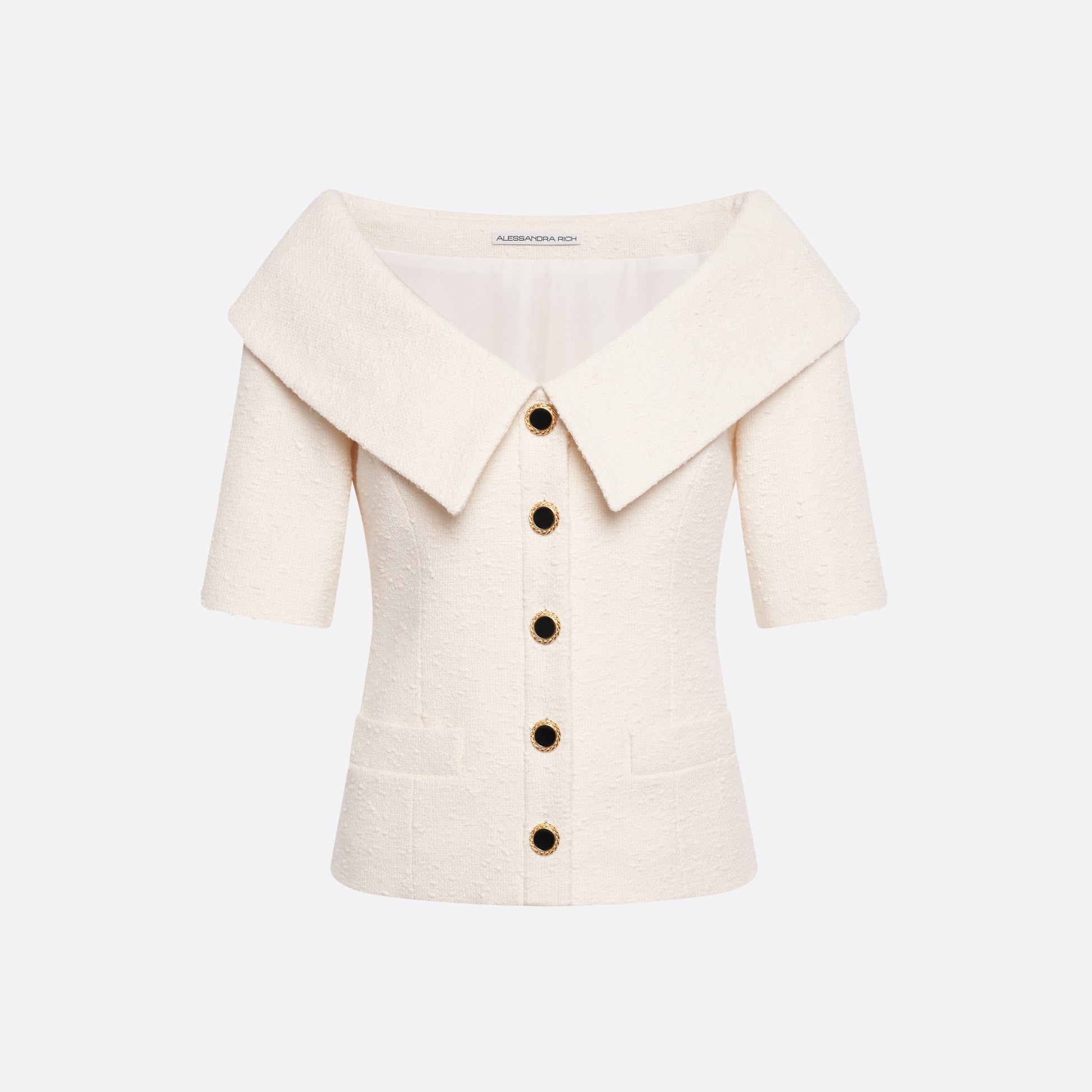 Ivory tweed bouclé off-shoulder jacket with a wide folded neckline and short sleeves. Finished with black and gold-tone buttons and welt pockets.