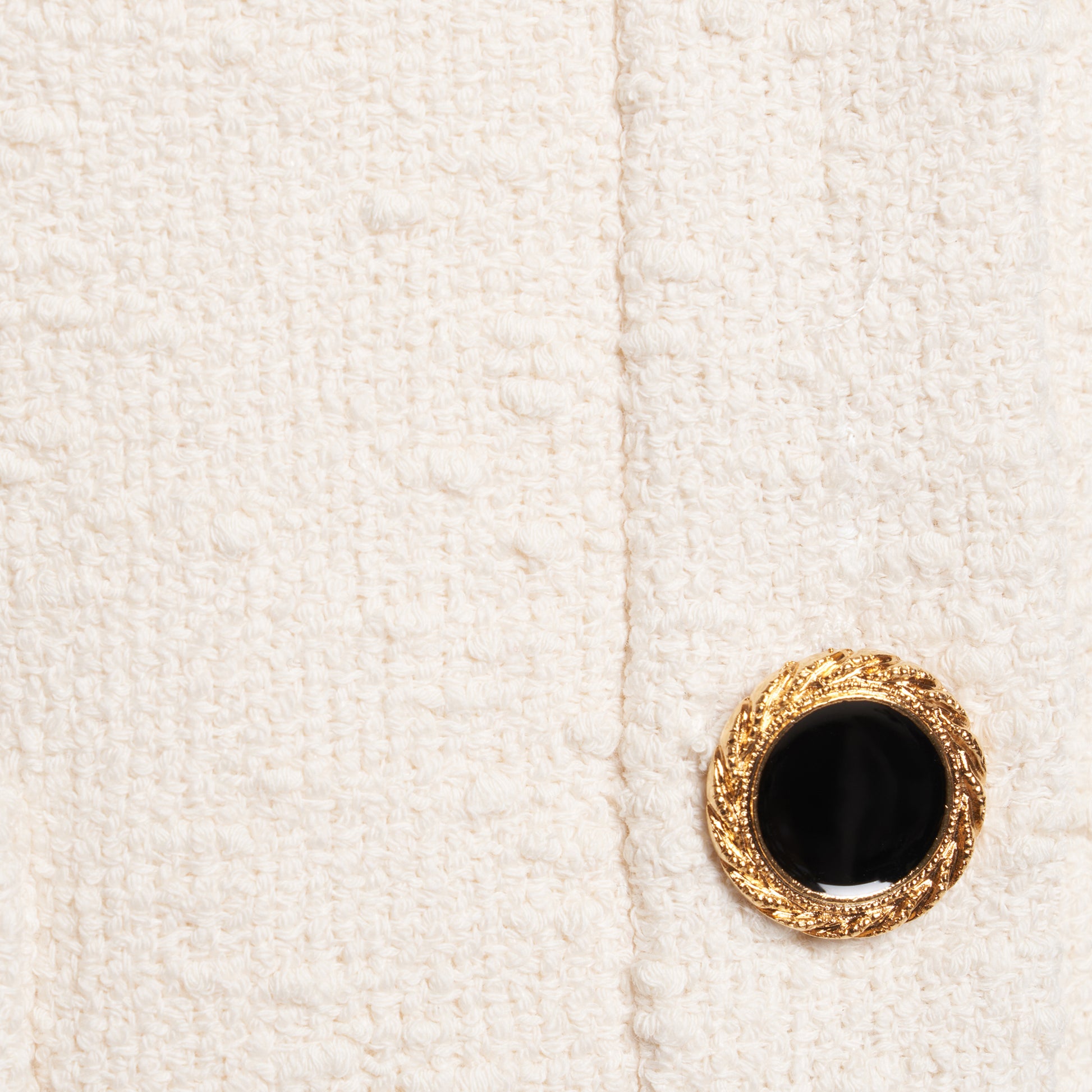 Ivory tweed bouclé off-shoulder jacket with a wide folded neckline and short sleeves. Finished with black and gold-tone buttons and welt pockets.