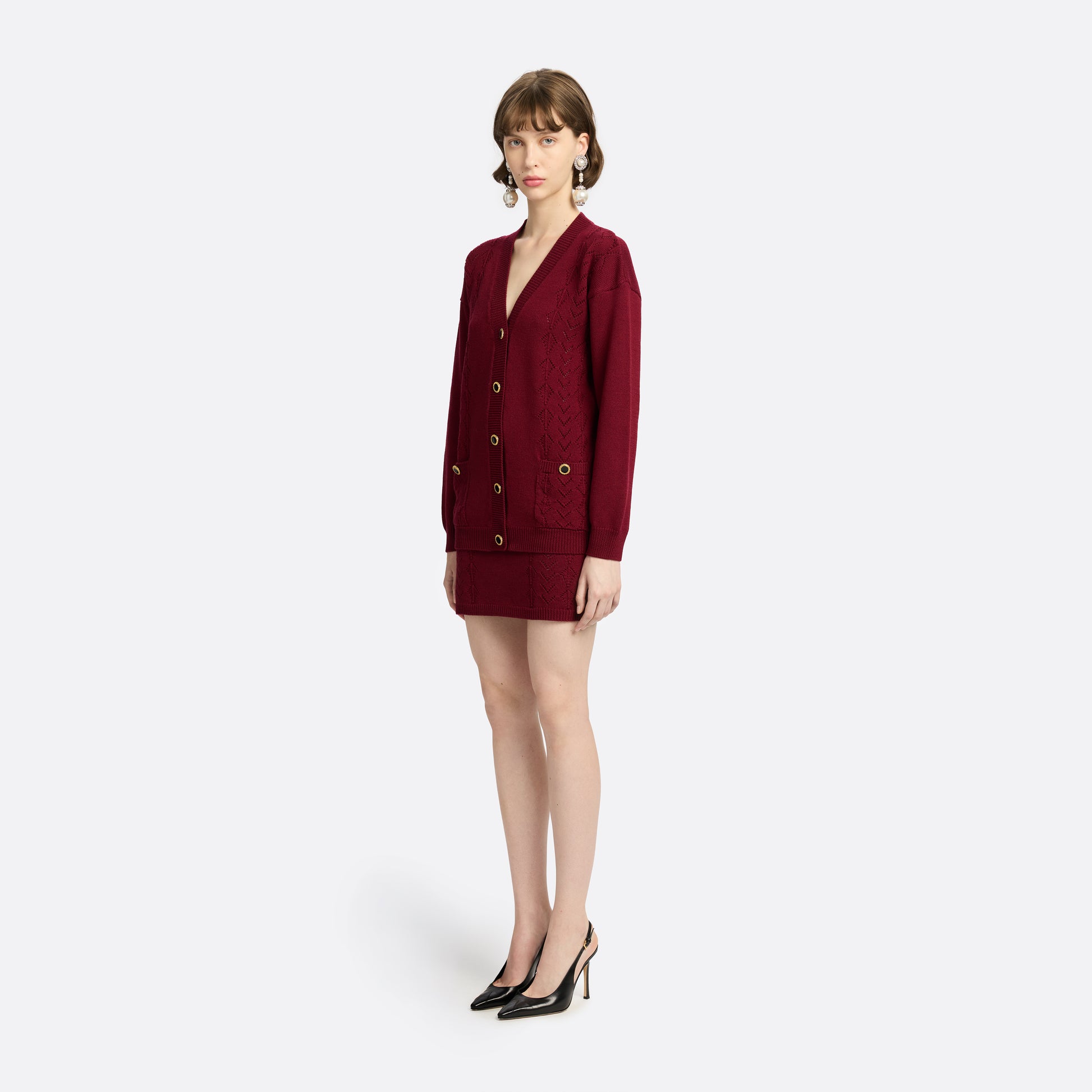 Bordeaux merino wool lace-knit cardigan cut to a relaxed silhouette with a V-neckline. Finished with patch pockets and black and gold-tone buttons.