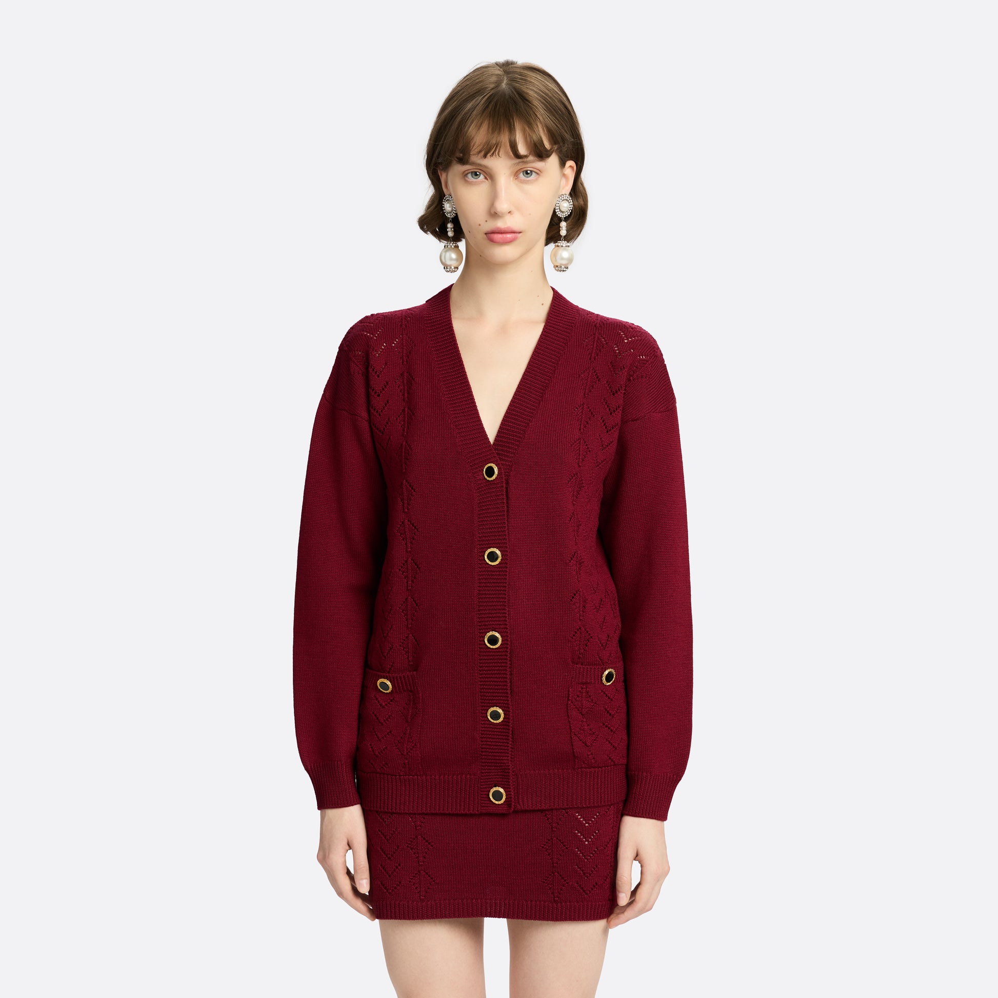 Bordeaux merino wool lace-knit cardigan cut to a relaxed silhouette with a V-neckline. Finished with patch pockets and black and gold-tone buttons.