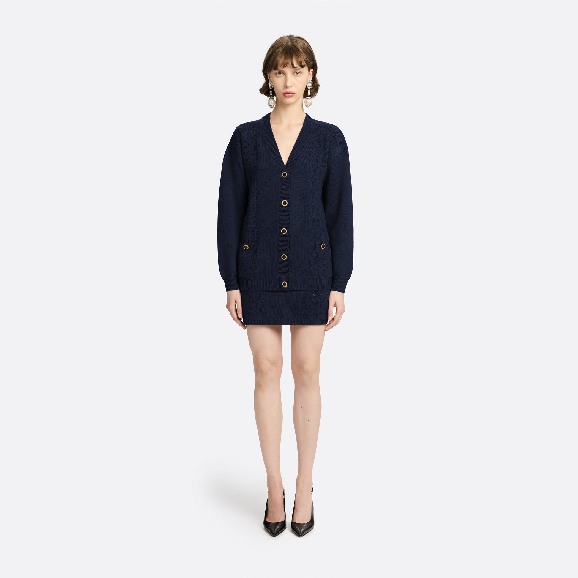Navy merino wool lace-knit cardigan cut to a relaxed silhouette with a V-neckline. Finished with patch pockets and black and gold-tone buttons.