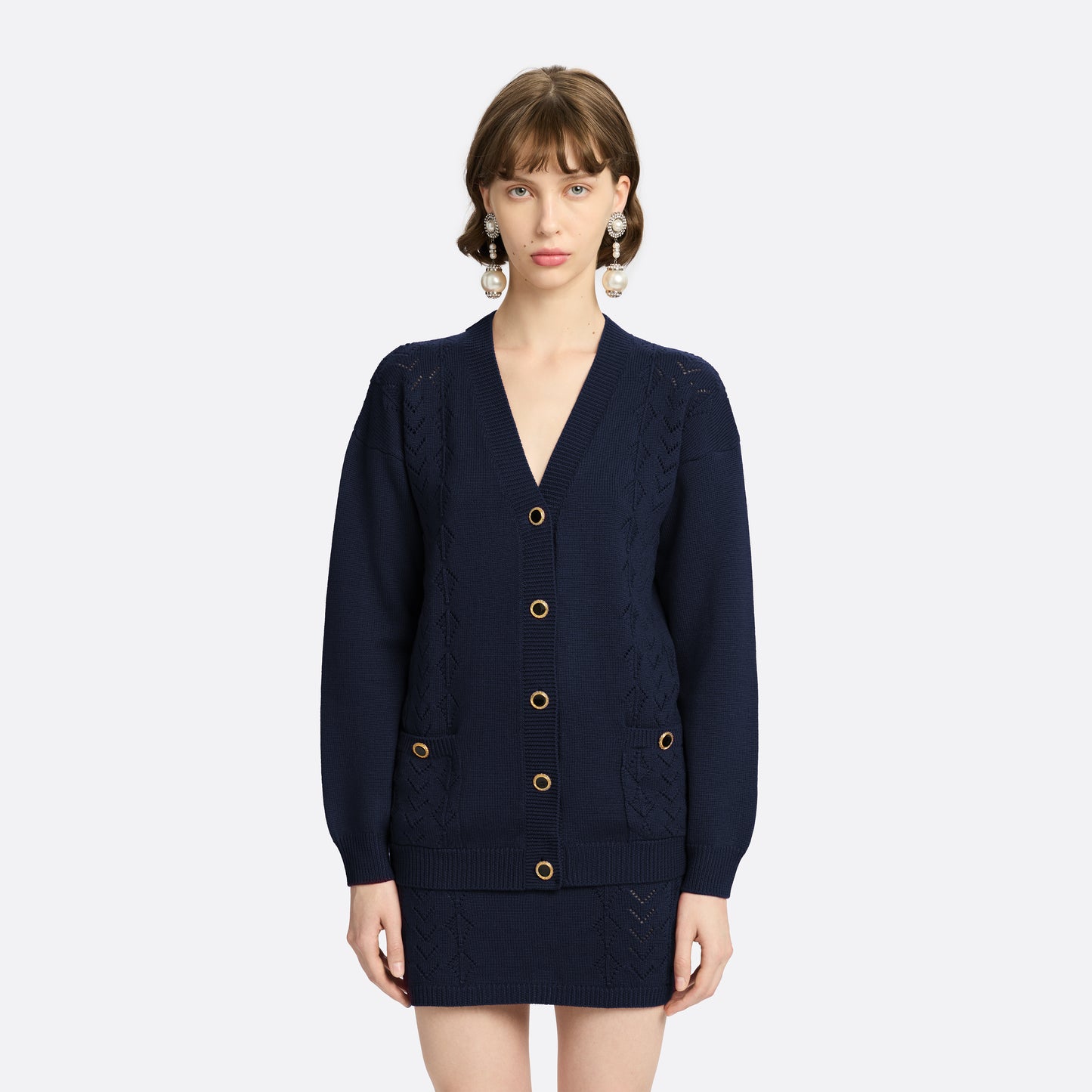 Navy merino wool lace-knit cardigan cut to a relaxed silhouette with a V-neckline. Finished with patch pockets and black and gold-tone buttons.