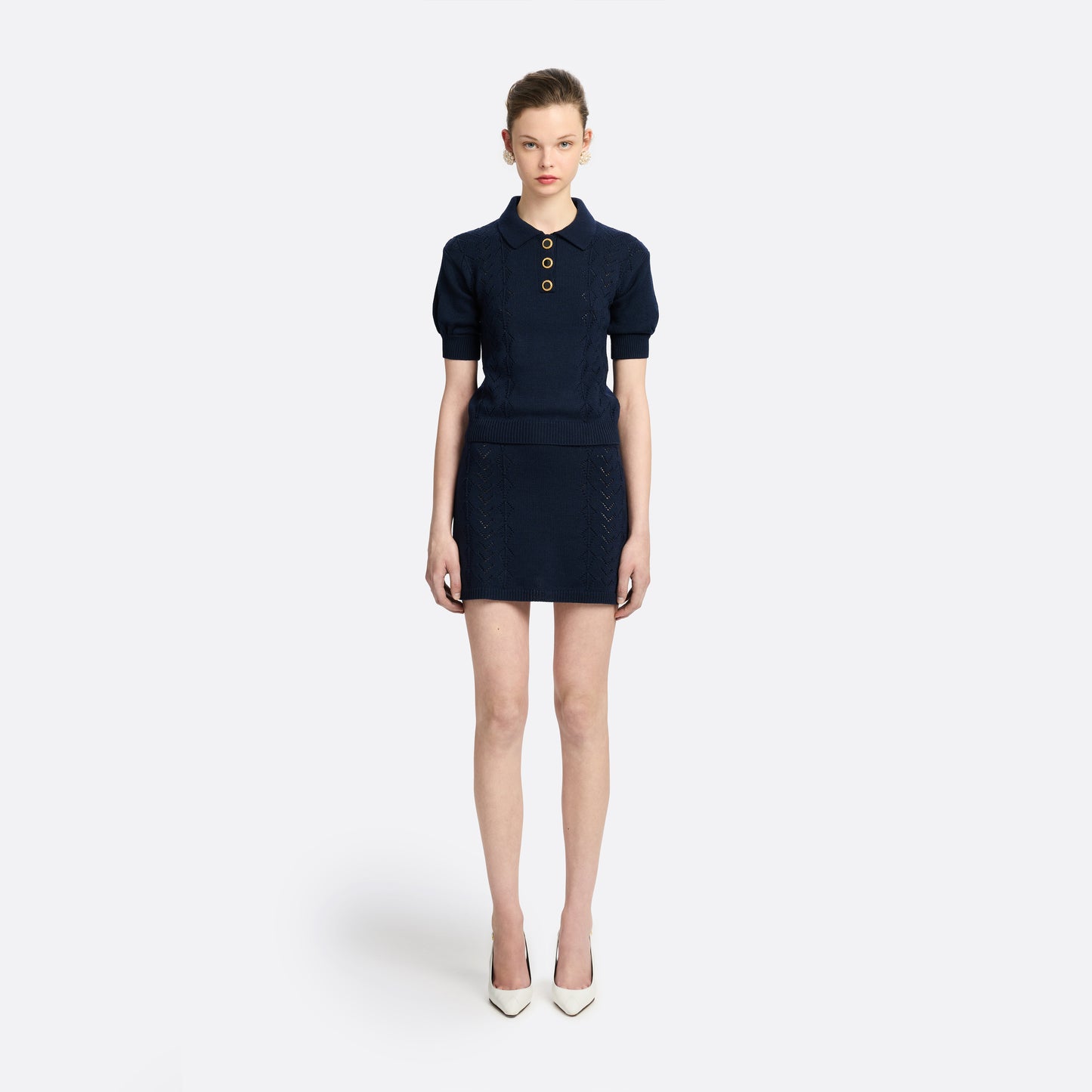 Navy blue merino wool lace-knit polo cut to a fitted silhouette with short puff sleeves and black and gold-tone buttons.