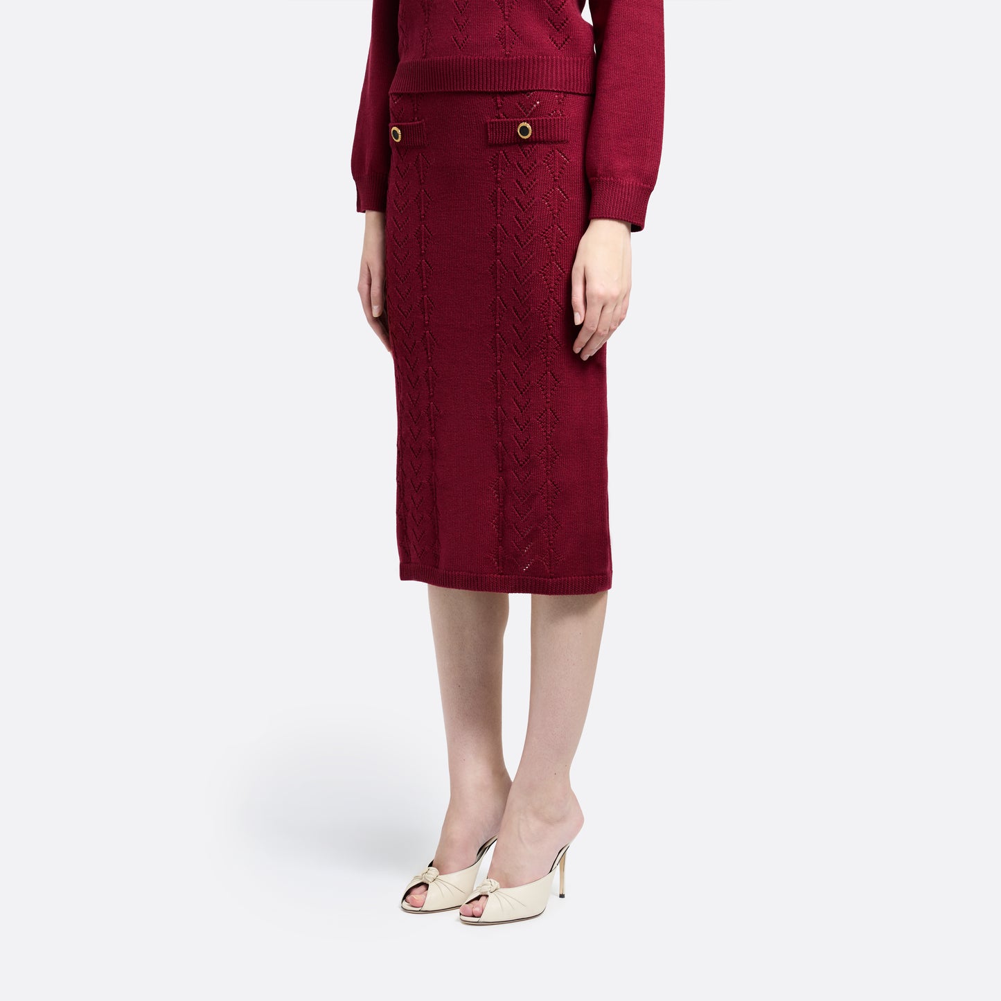 Bordeaux merino wool lace-knit midi skirt cut in a fitted silhouette. Finished with decorative pockets and black and gold-tone buttons.