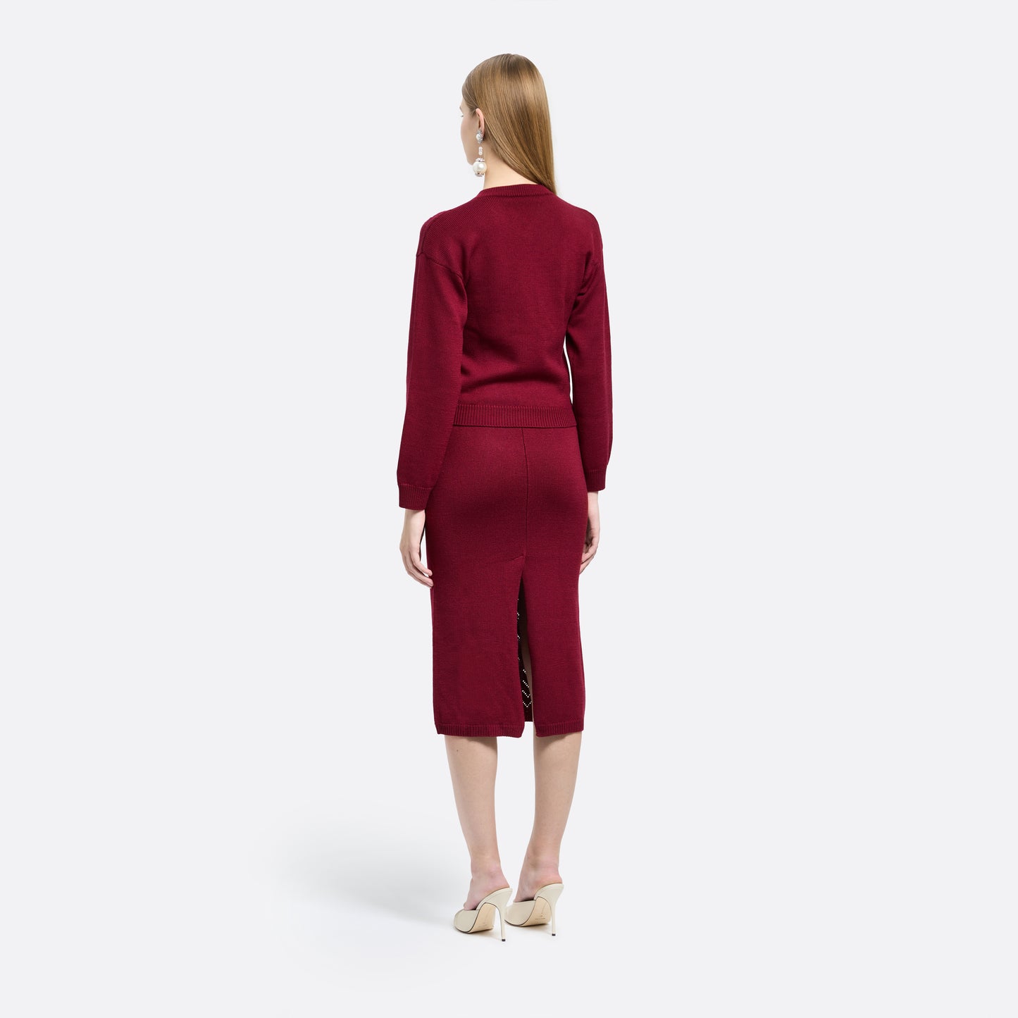 Bordeaux merino wool lace-knit midi skirt cut in a fitted silhouette. Finished with decorative pockets and black and gold-tone buttons.