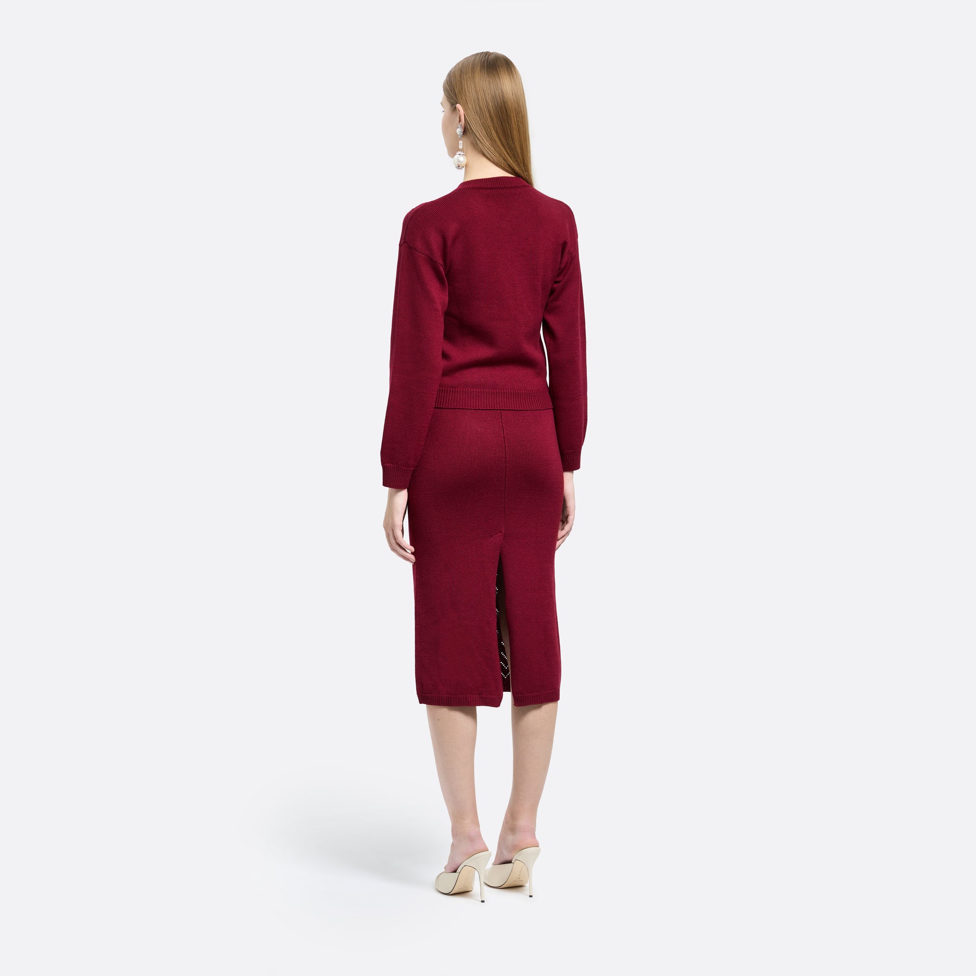 Bordeaux merino wool lace-knit midi skirt cut in a fitted silhouette. Finished with decorative pockets and black and gold-tone buttons.